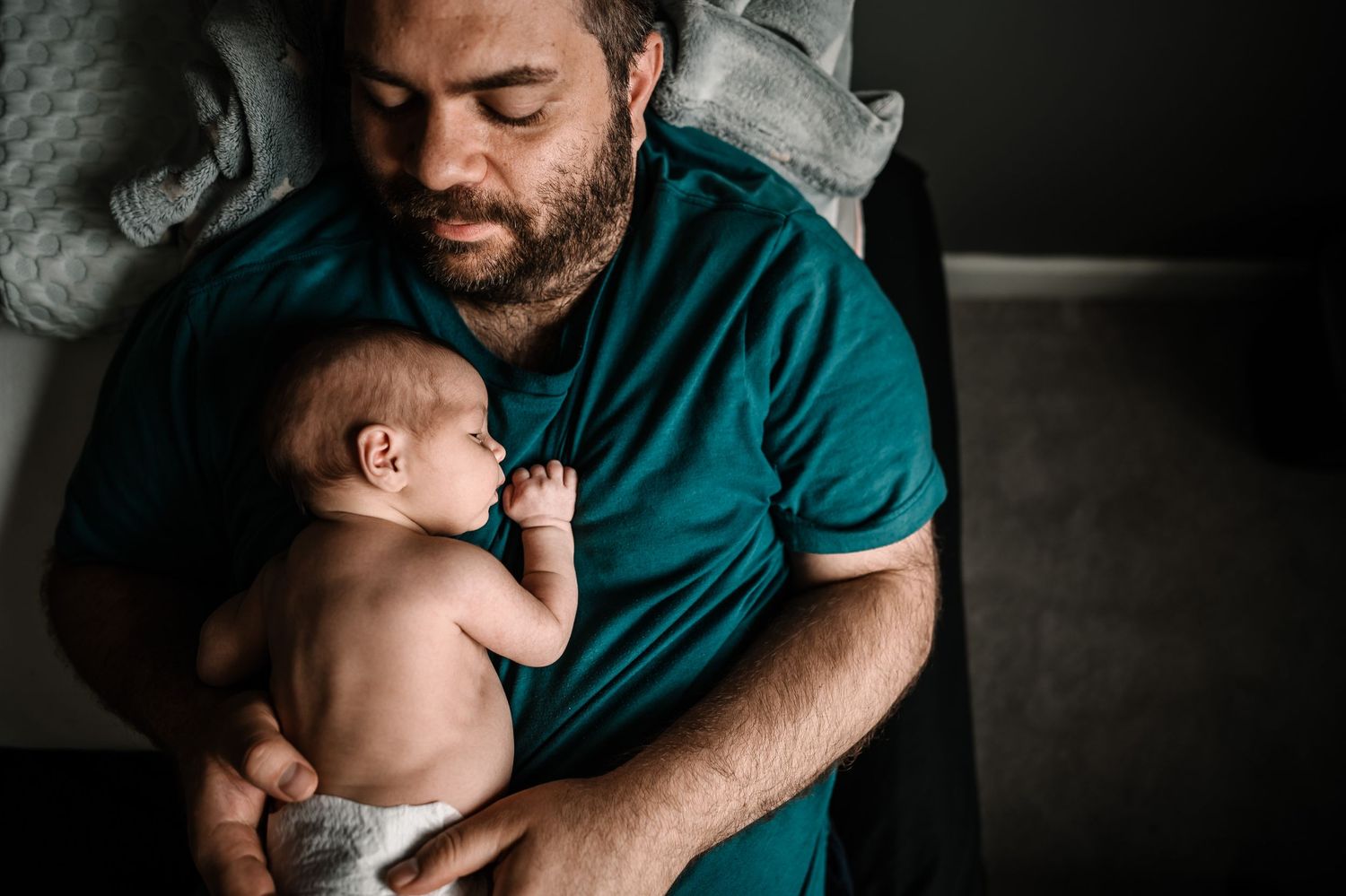 Father Lying On Bed Holding Baby On His Chest