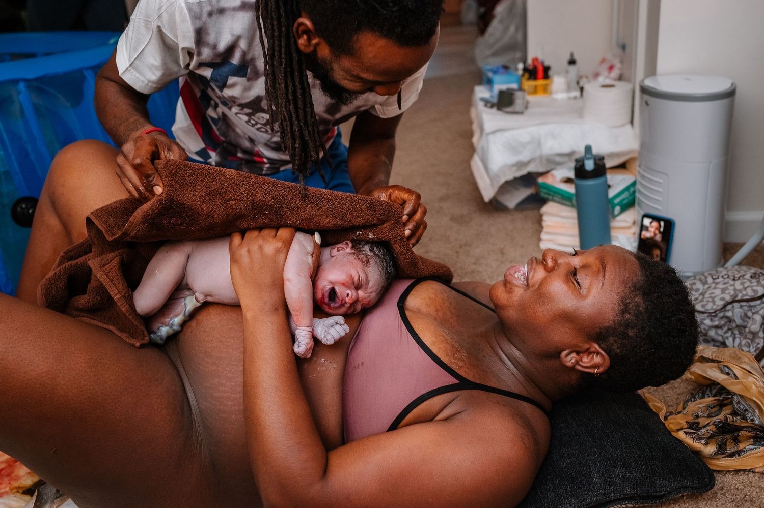 Mother And Father Smiling After Birthing Baby On The Floor At Home Birth, Gender Reveal
