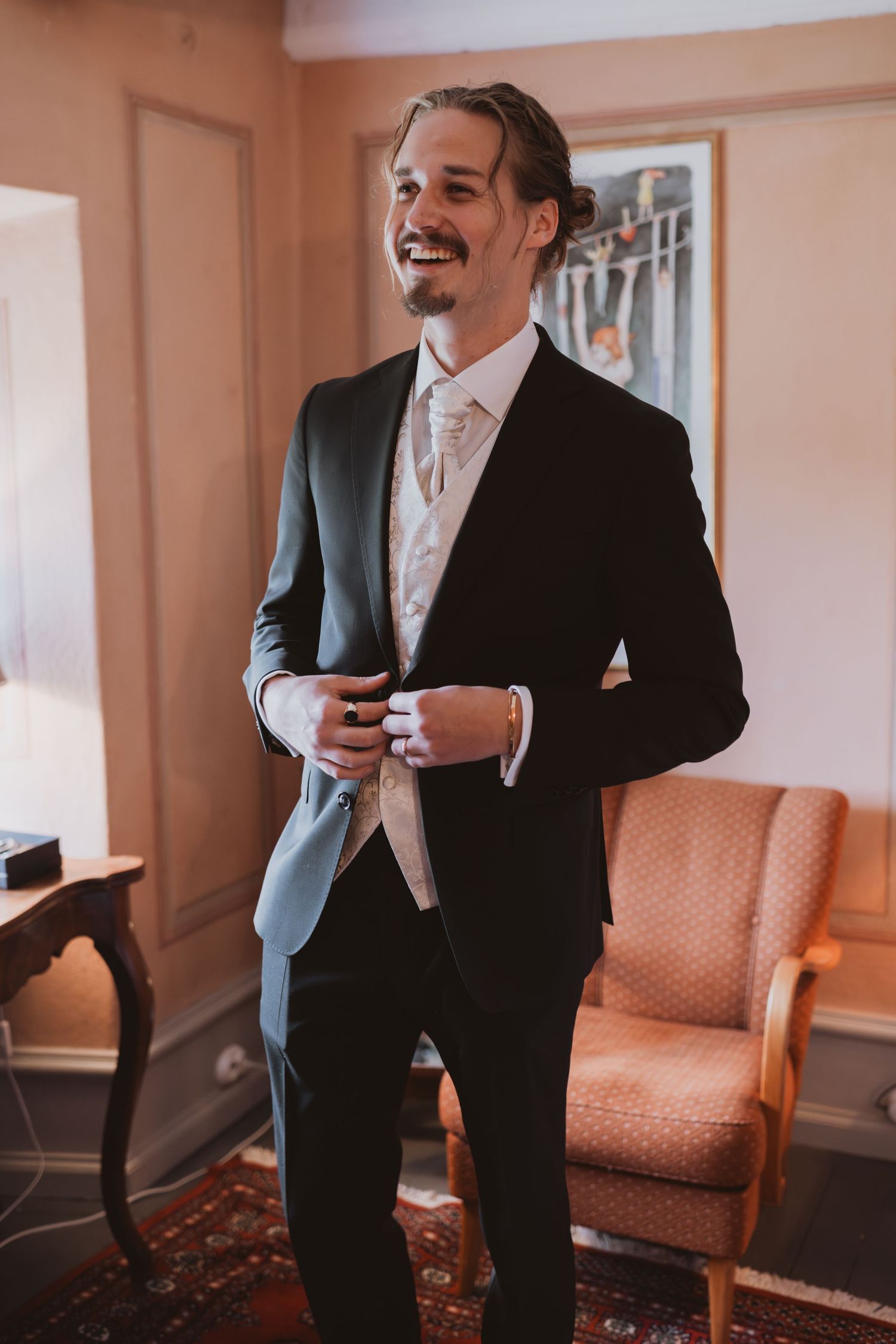 Formal portrait in classic black suit and tie in an elegant indoor setting.