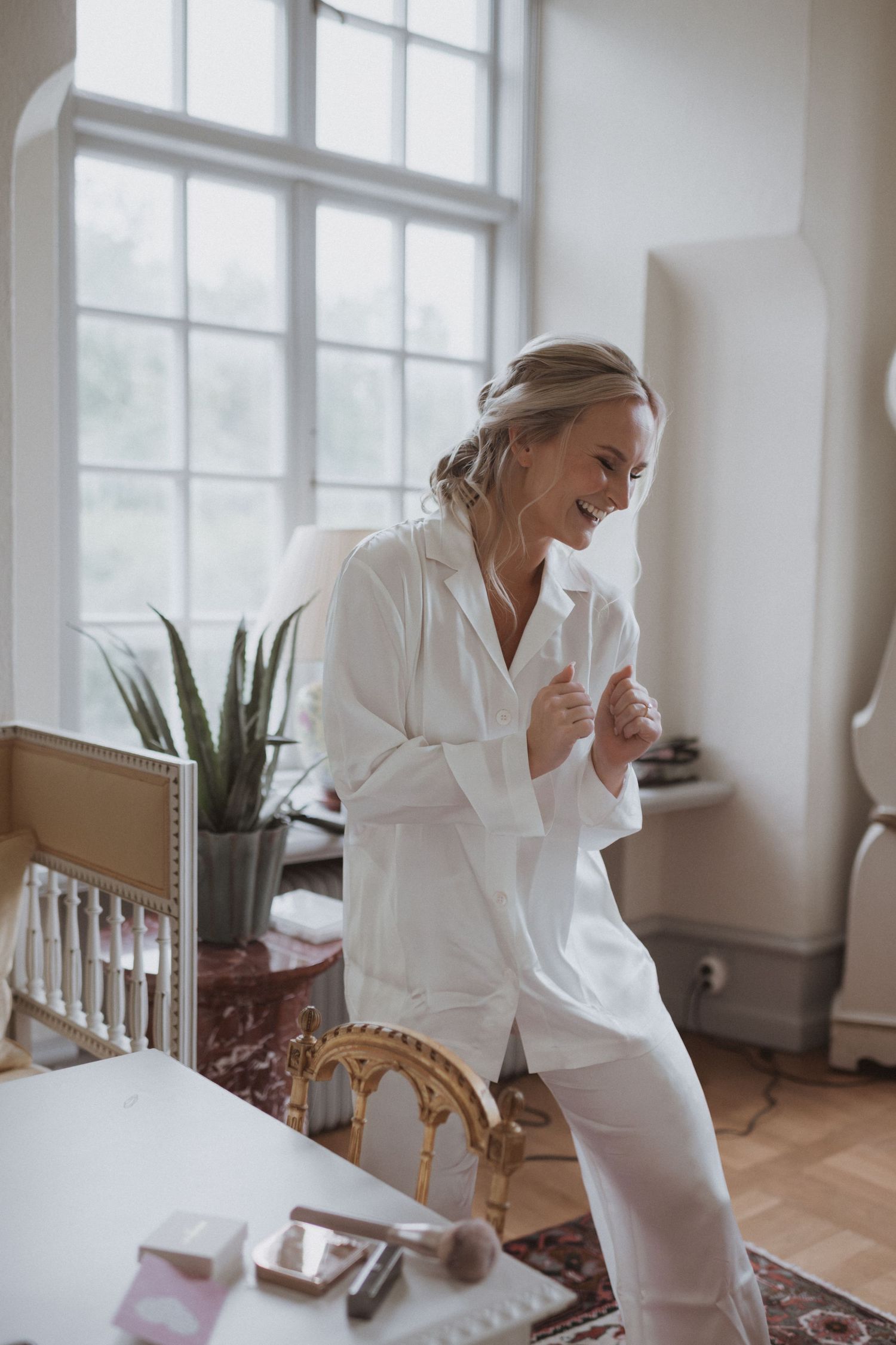 Candid morning moment in bright white room with window light and indoor plants.