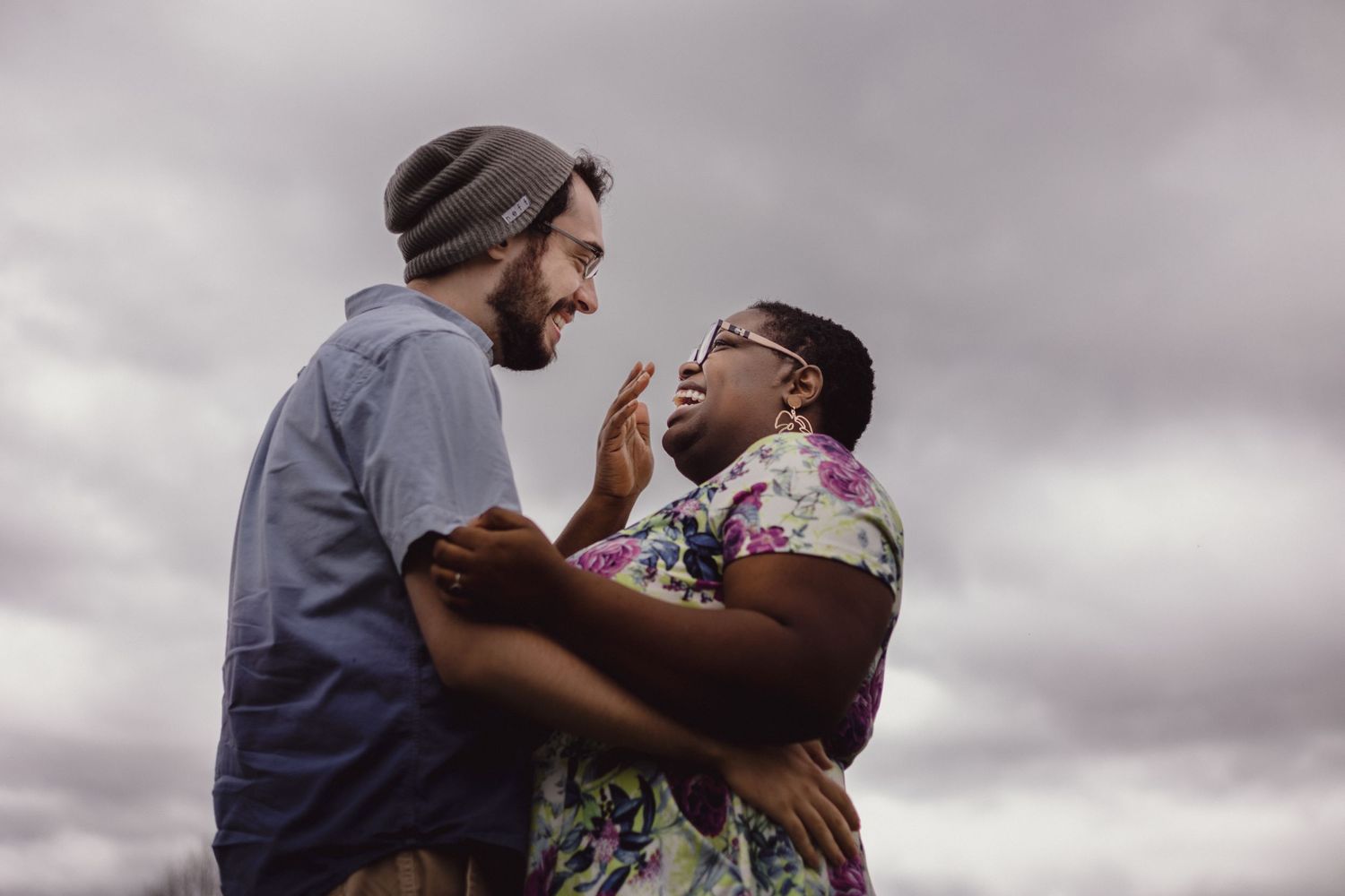 A tender emotional moment between two people captured against a cloudy sky.