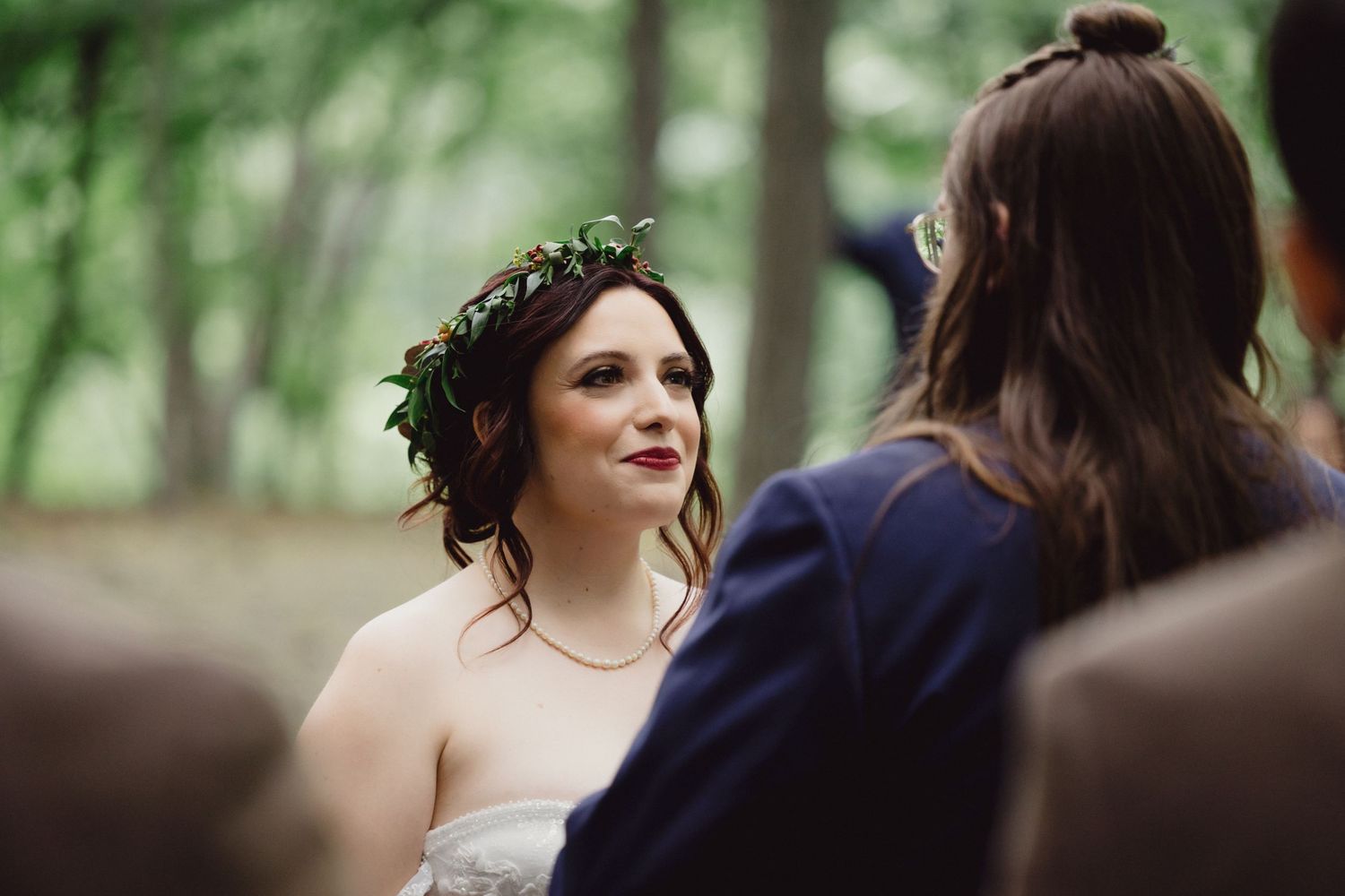 A woodland wedding ceremony scene with natural greenery and decorative elements.