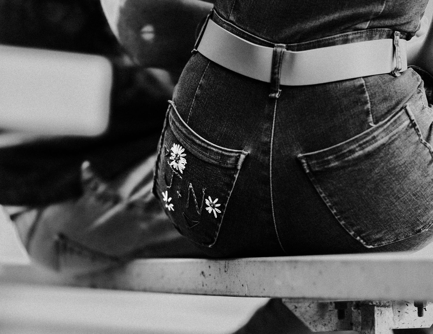 Black and white detail shot of decorated back pocket on denim jeans.