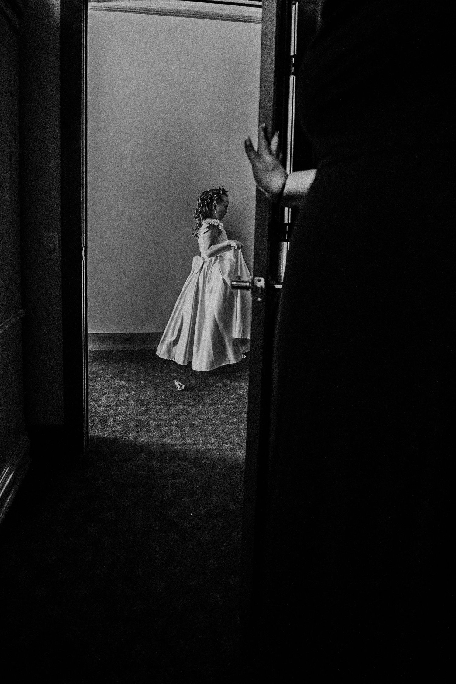 A small child in a flowing dress twirls in a doorway.