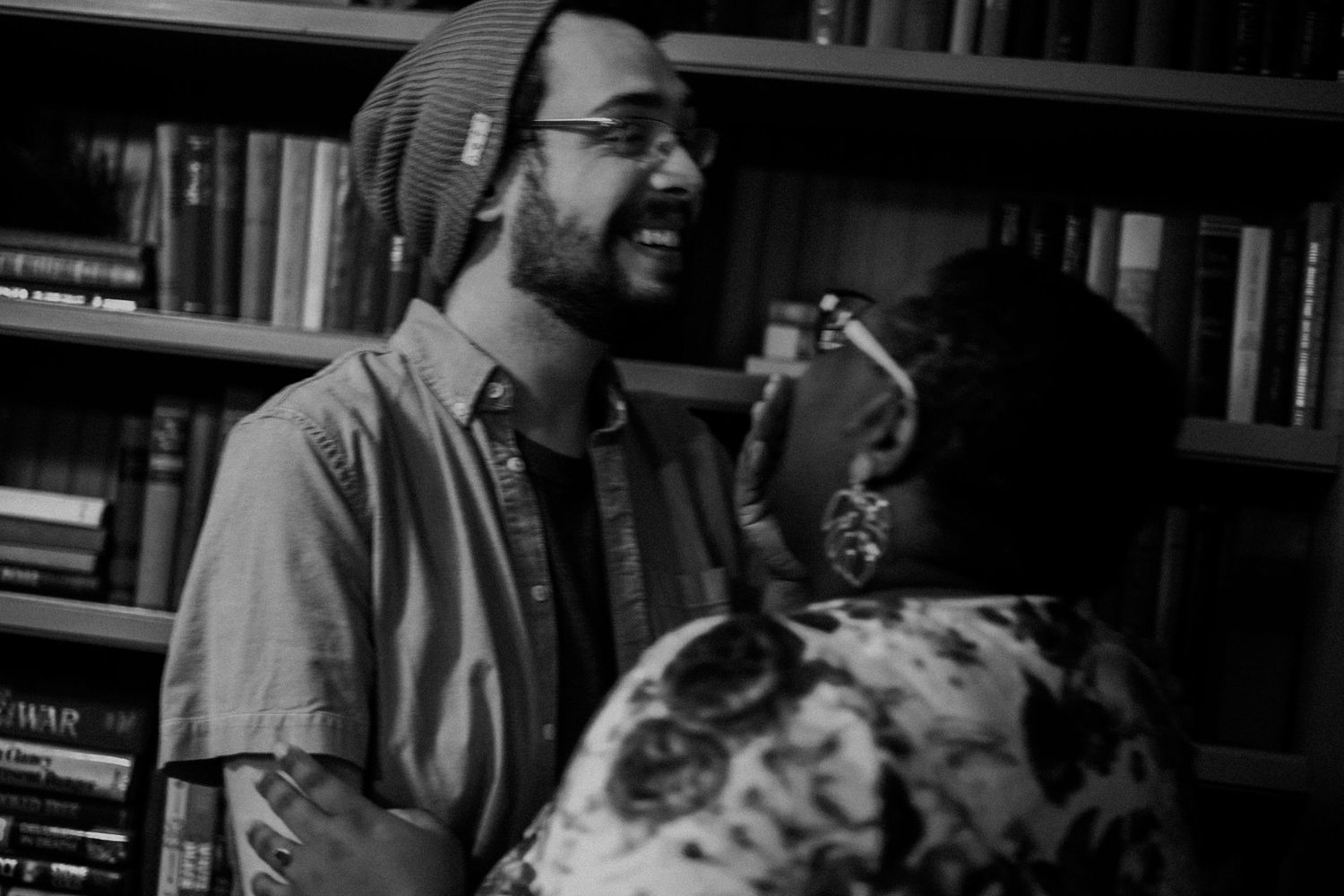 A candid black and white moment shared between two people in a library setting.