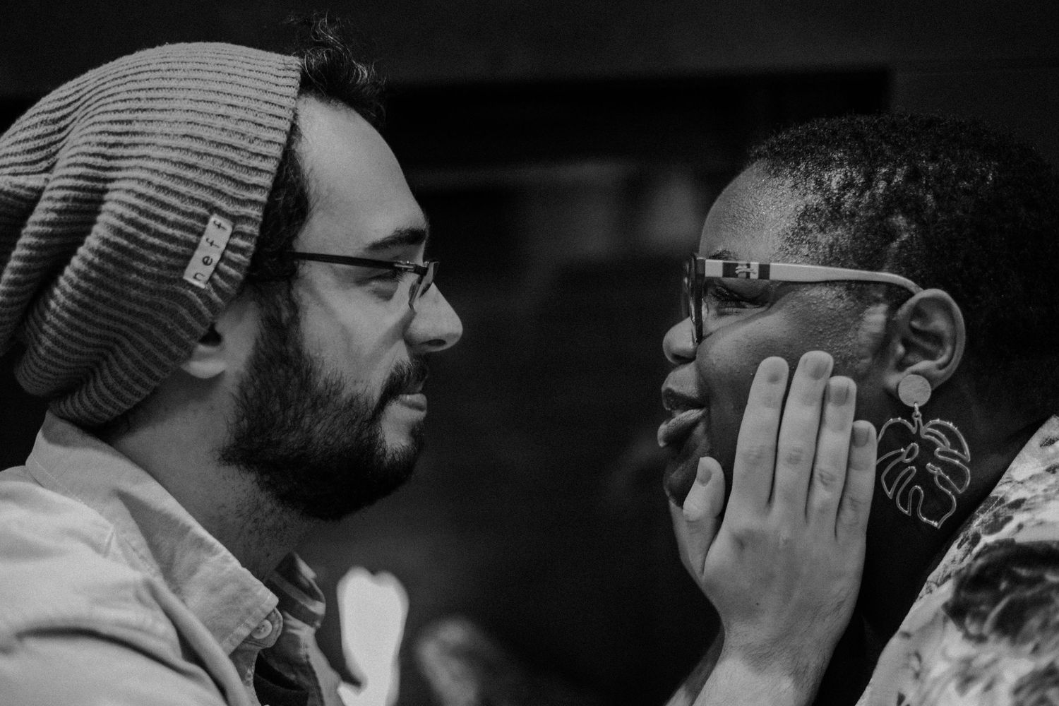 An intimate black and white portrait showing two people sharing a close emotional moment.