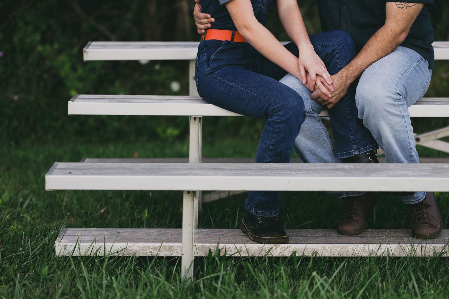 Cropped view of two people sitting together on outdoor bleachers.