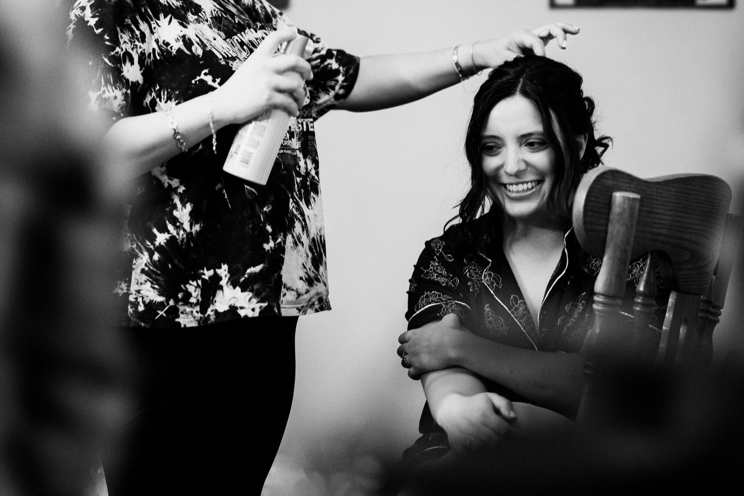 A candid black and white photo of laughter during wedding preparations.