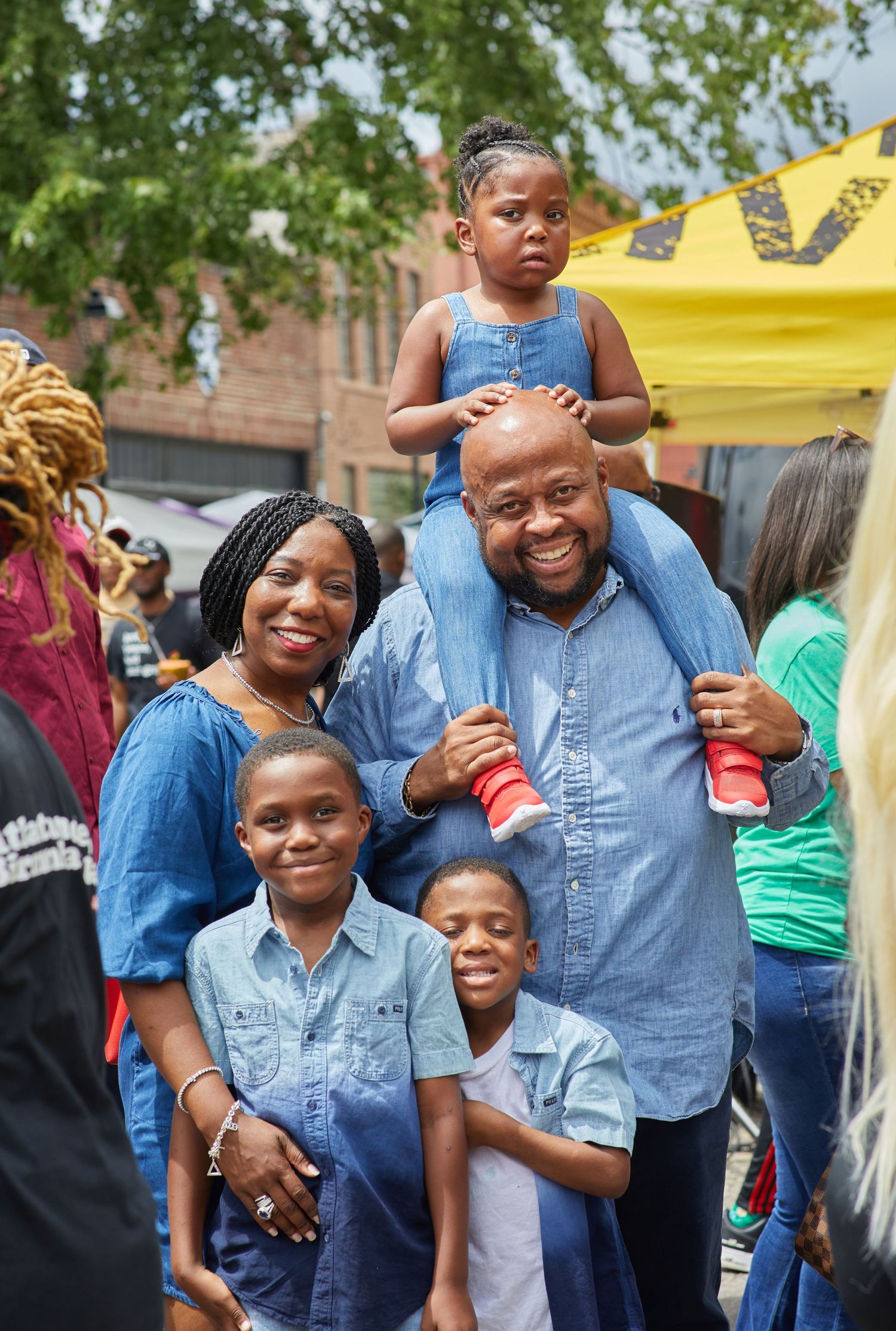 Family of five wearing coordinated blue outfits at outdoor community gathering.