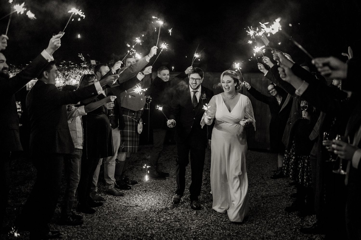 Laughing bride and groom at sparkler exit at a winter wedding in Hertfordshire. Absolute joy for the newly weds.