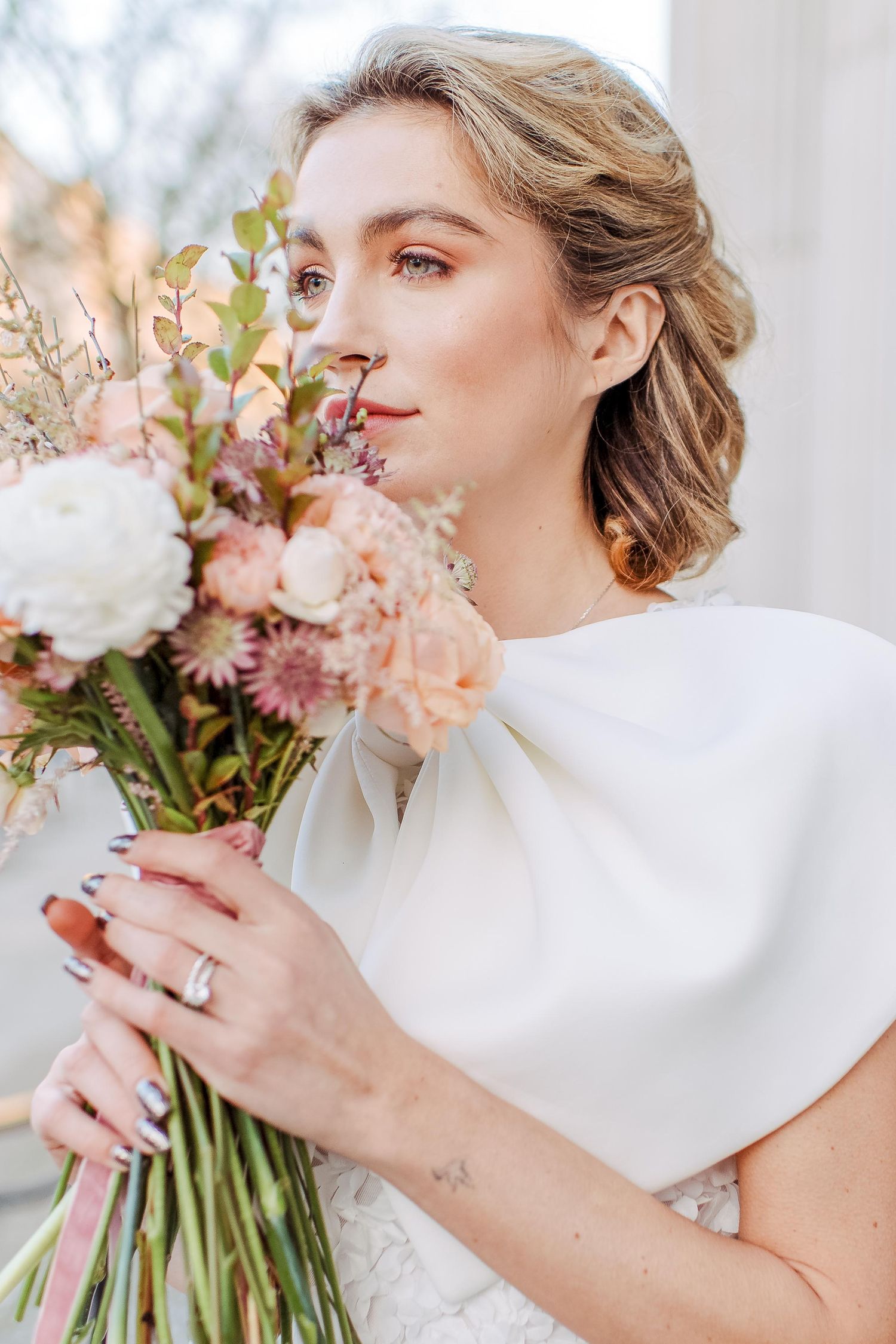Beautiful bridal portrait with elegant white dress, soft pink and peach bouquet against ethereal background at the Marylebone Town Hall.