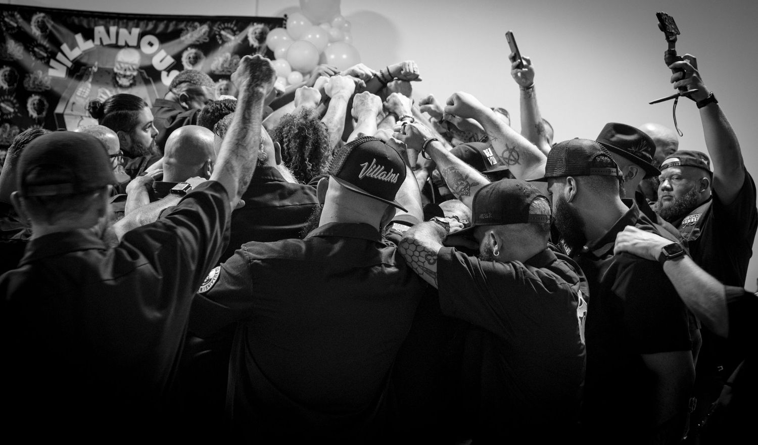 Black and white crowd scene at concert with raised arms and energetic atmosphere.