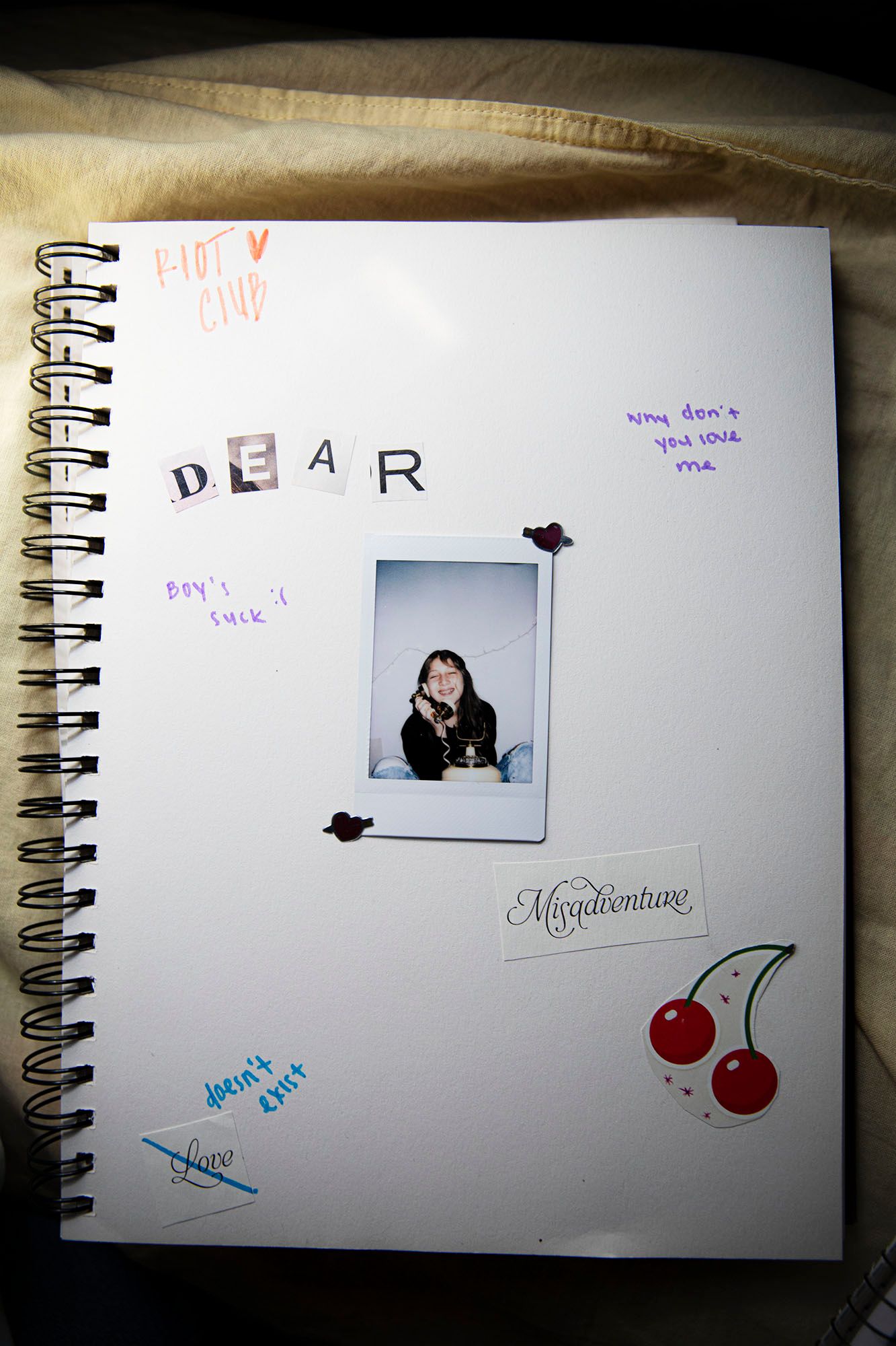 A spiral notebook page decorated with handwriting, a polaroid photo, and cherry illustrations.