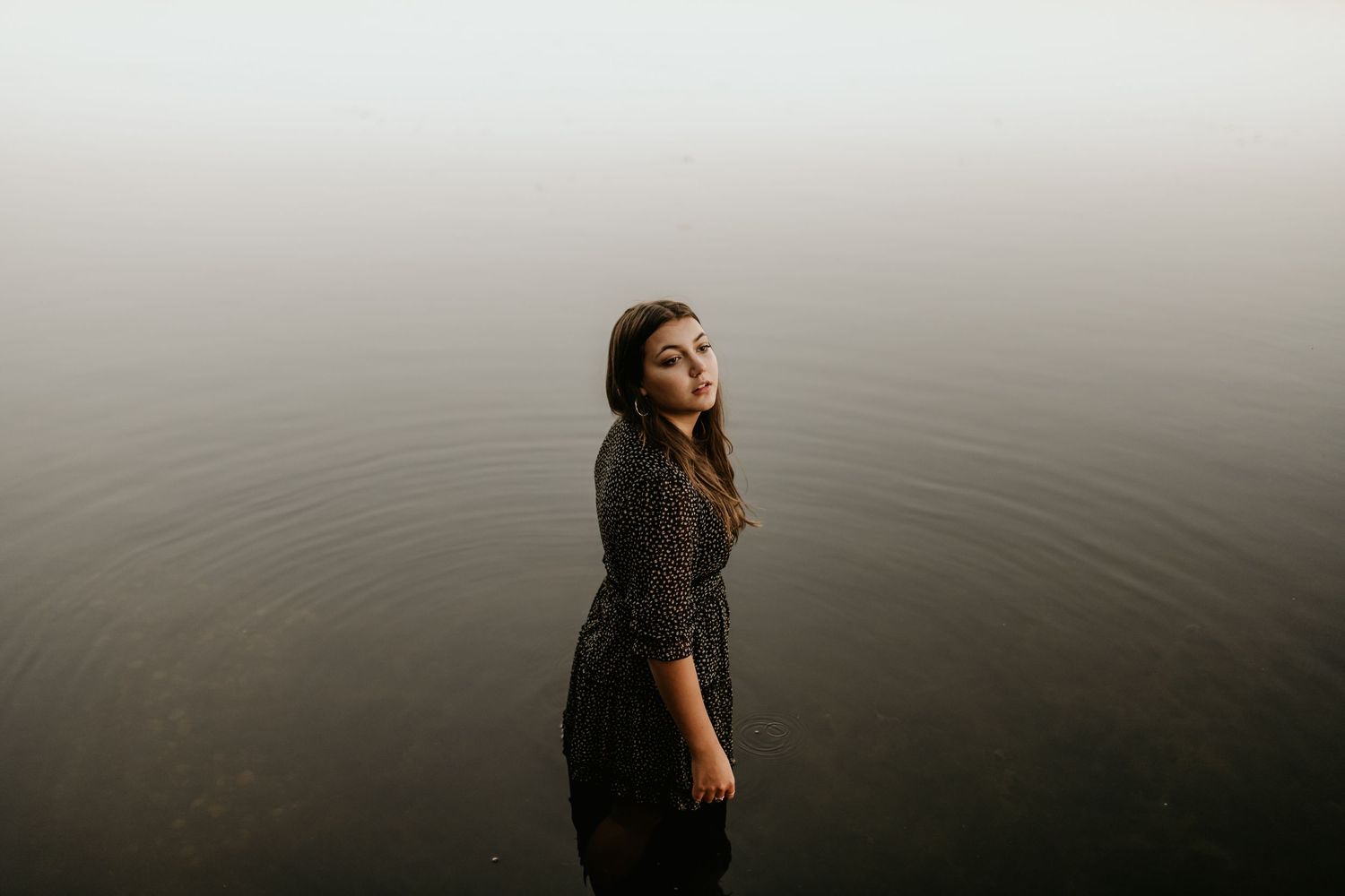 Creative portrait by still water during golden hour with dramatic atmosphere.