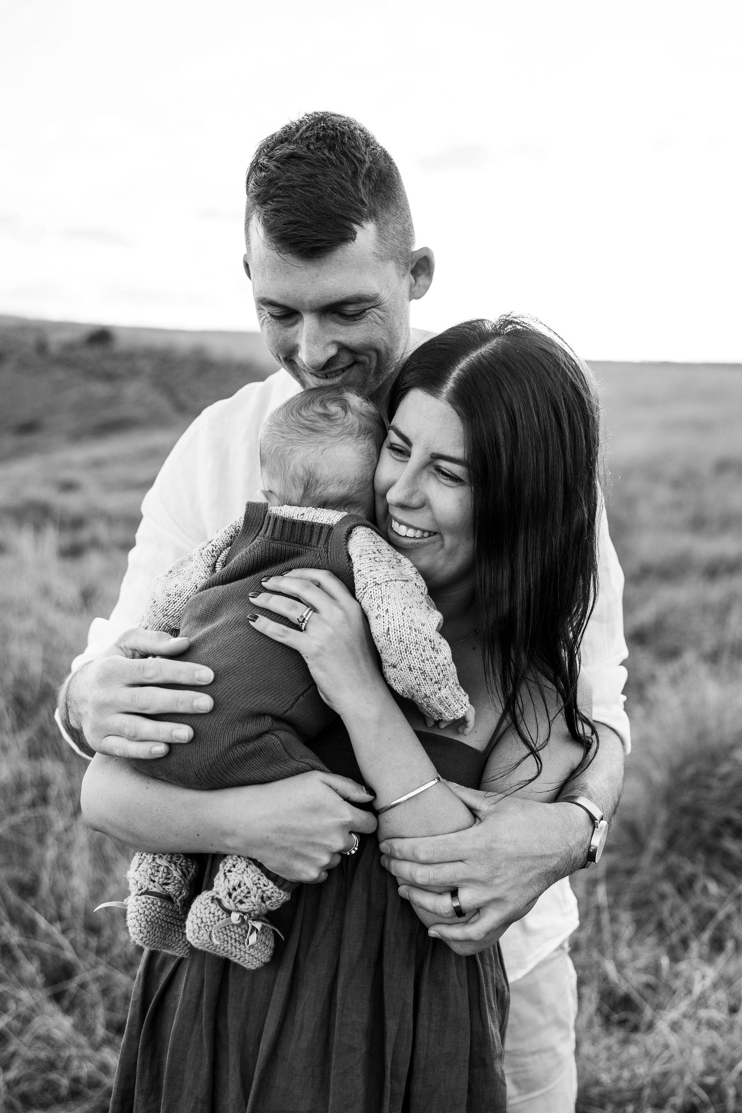 Candid black and white engagement photos showing joyful laughter in a field.