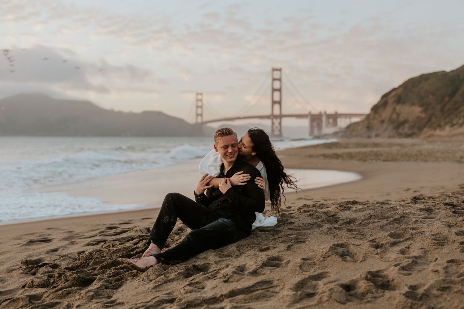 San Francisco Engagment Photographer - couple sitting on beach with Golden Gate Bridge behind them