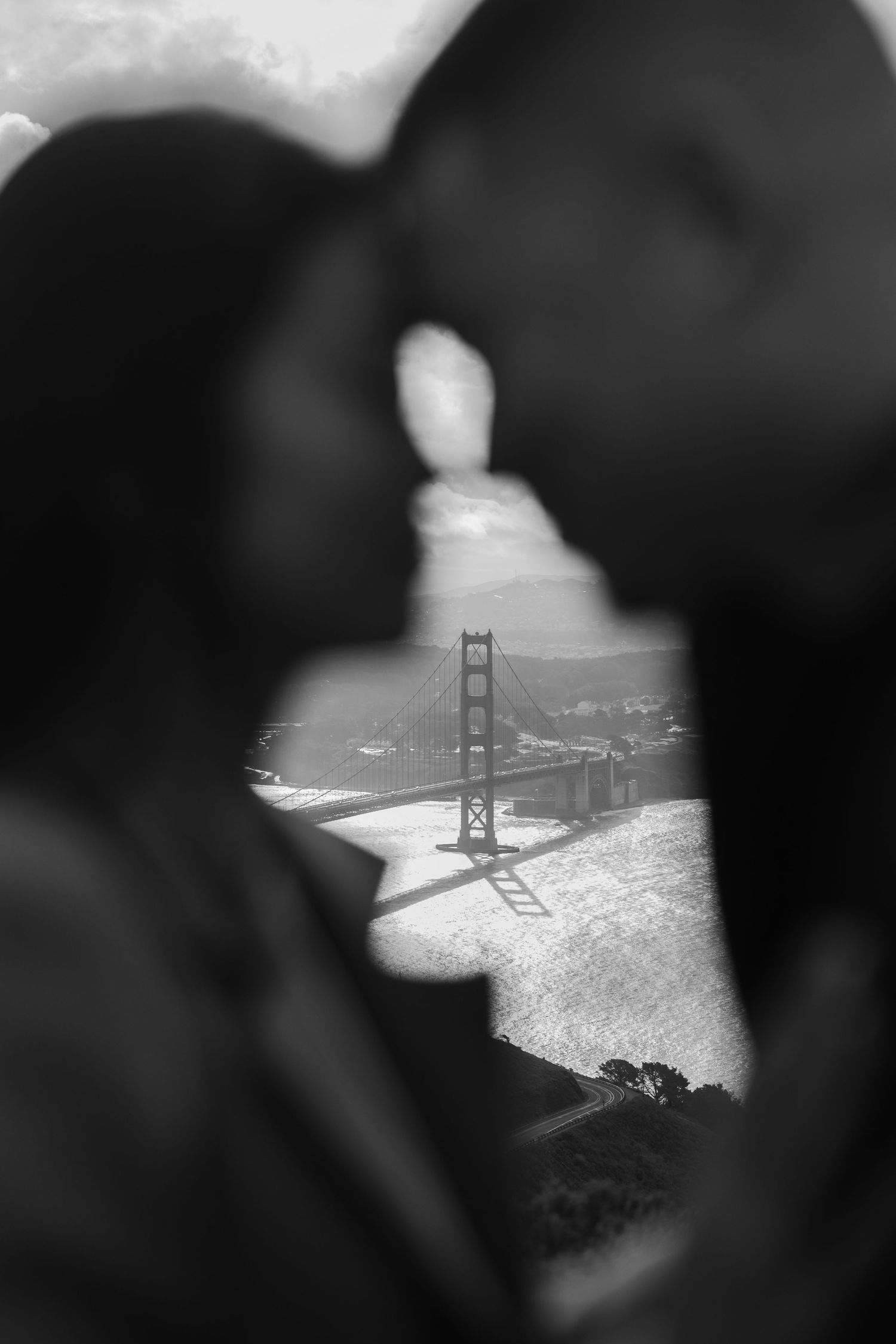 couple out of focus with for heads together, the Golden Gate Bridge in focus between them