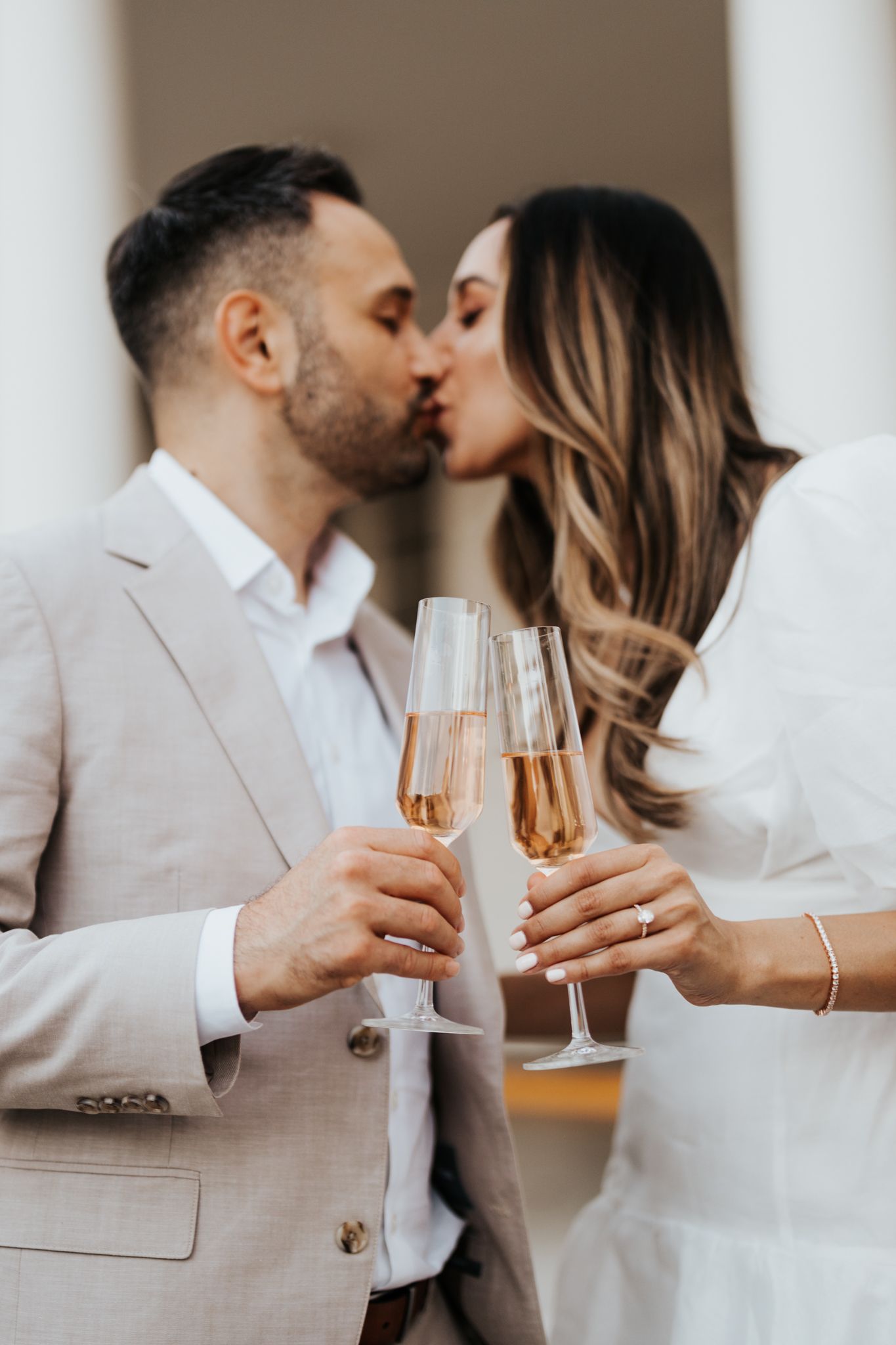 couple kissing with the focus on their champagne flutes clinking