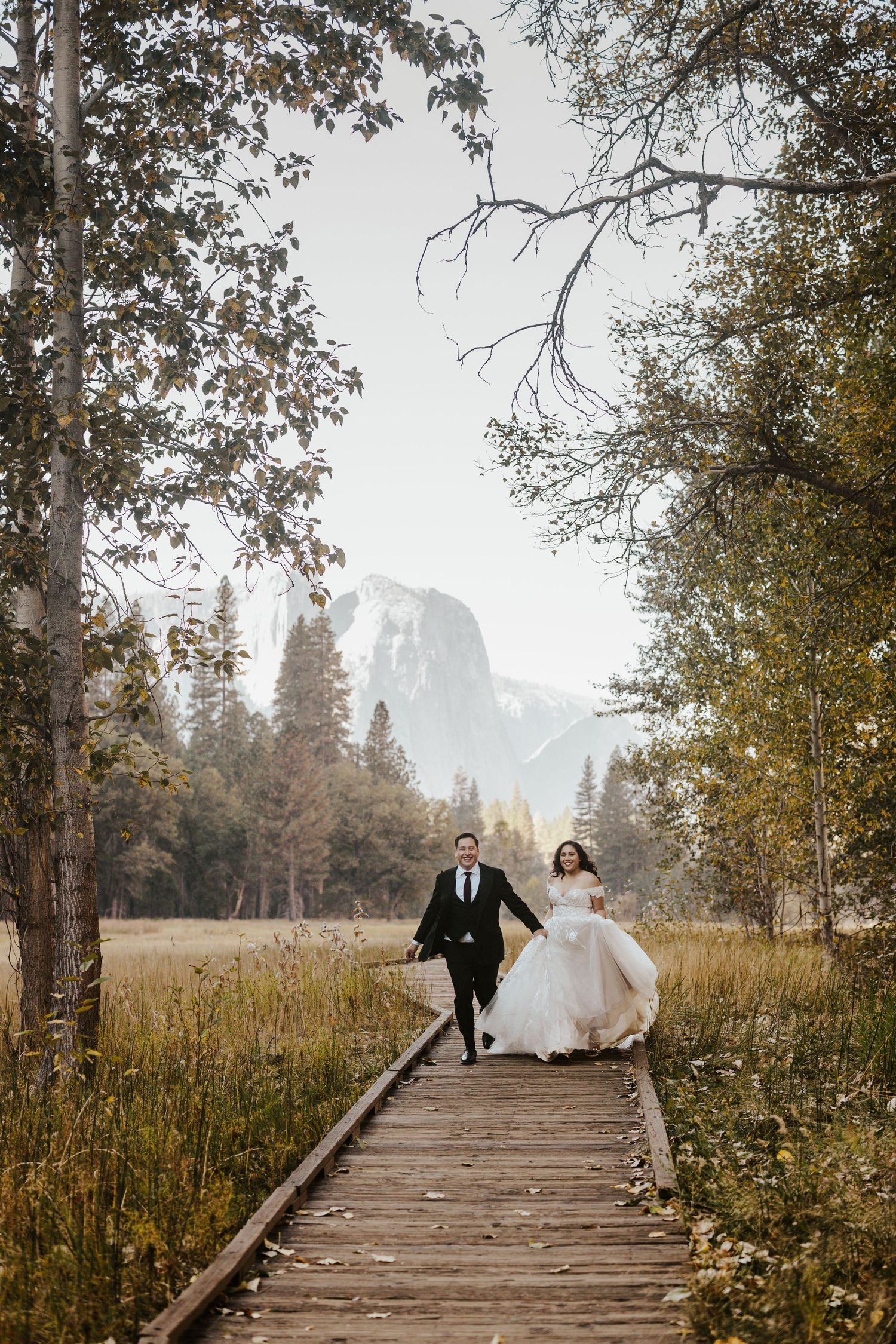 Yosemite Elopement Photographer - bride and groom running through Yosemite valley, half dome in the distance