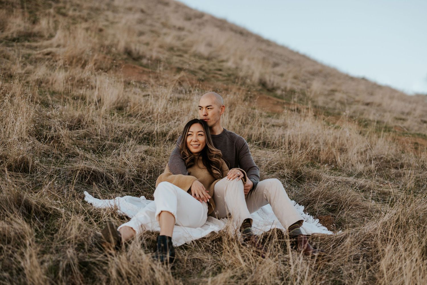 couple sitting on a blanket snuggling into each other on the side of Mount Tamalpais