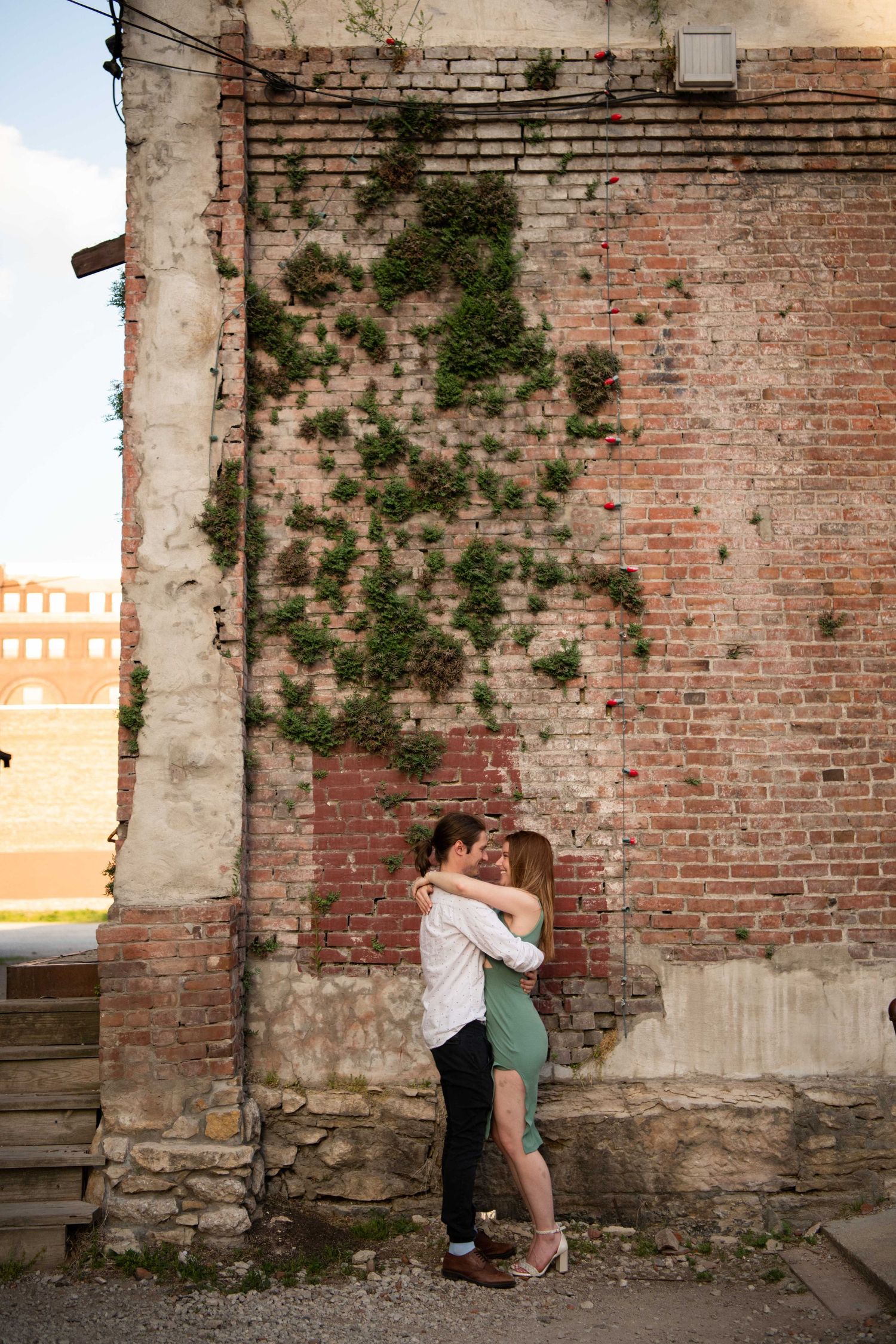 Intimate embrace against weathered brick wall with climbing ivy.