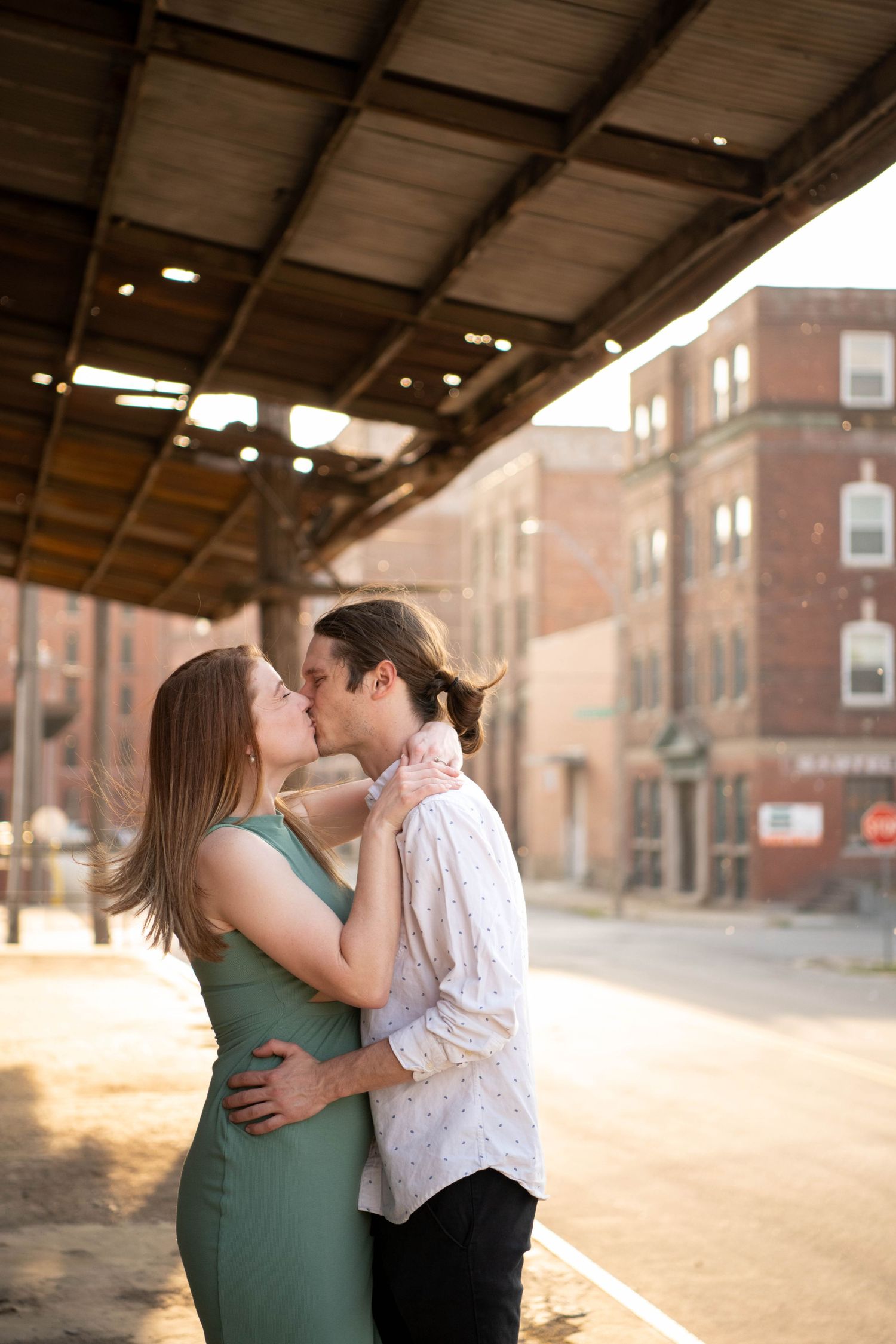 A romantic kiss under an industrial overhang during golden hour.