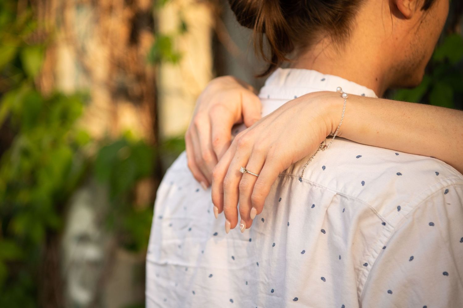 Close-up detail of hands embracing on a polka dot white shirt.