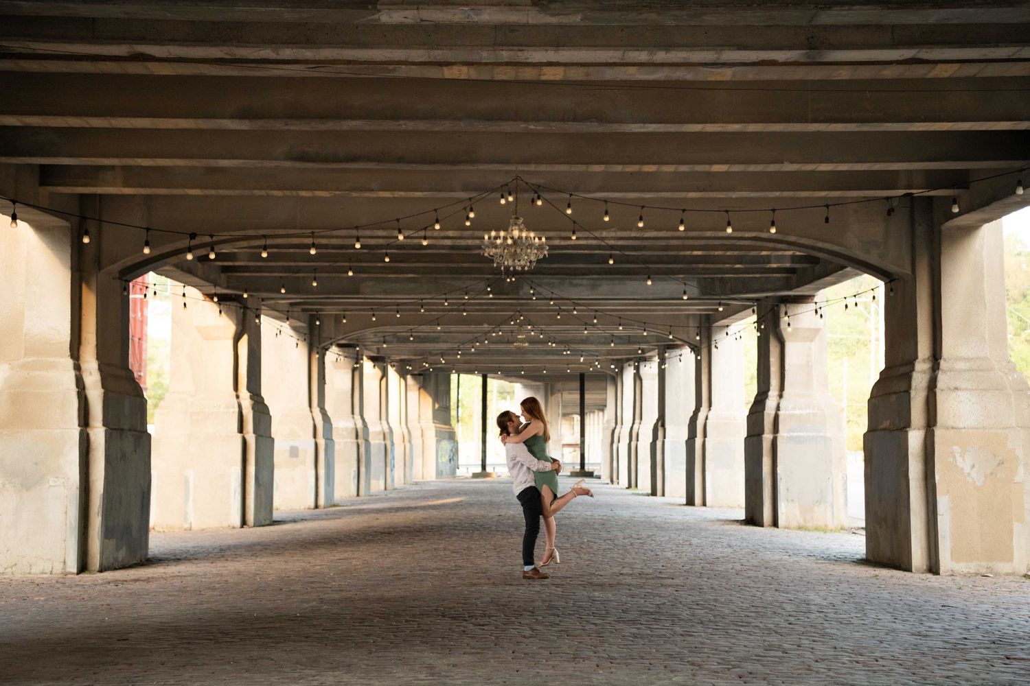 Romantic embrace in tunnel with string lights creating magical ambiance.