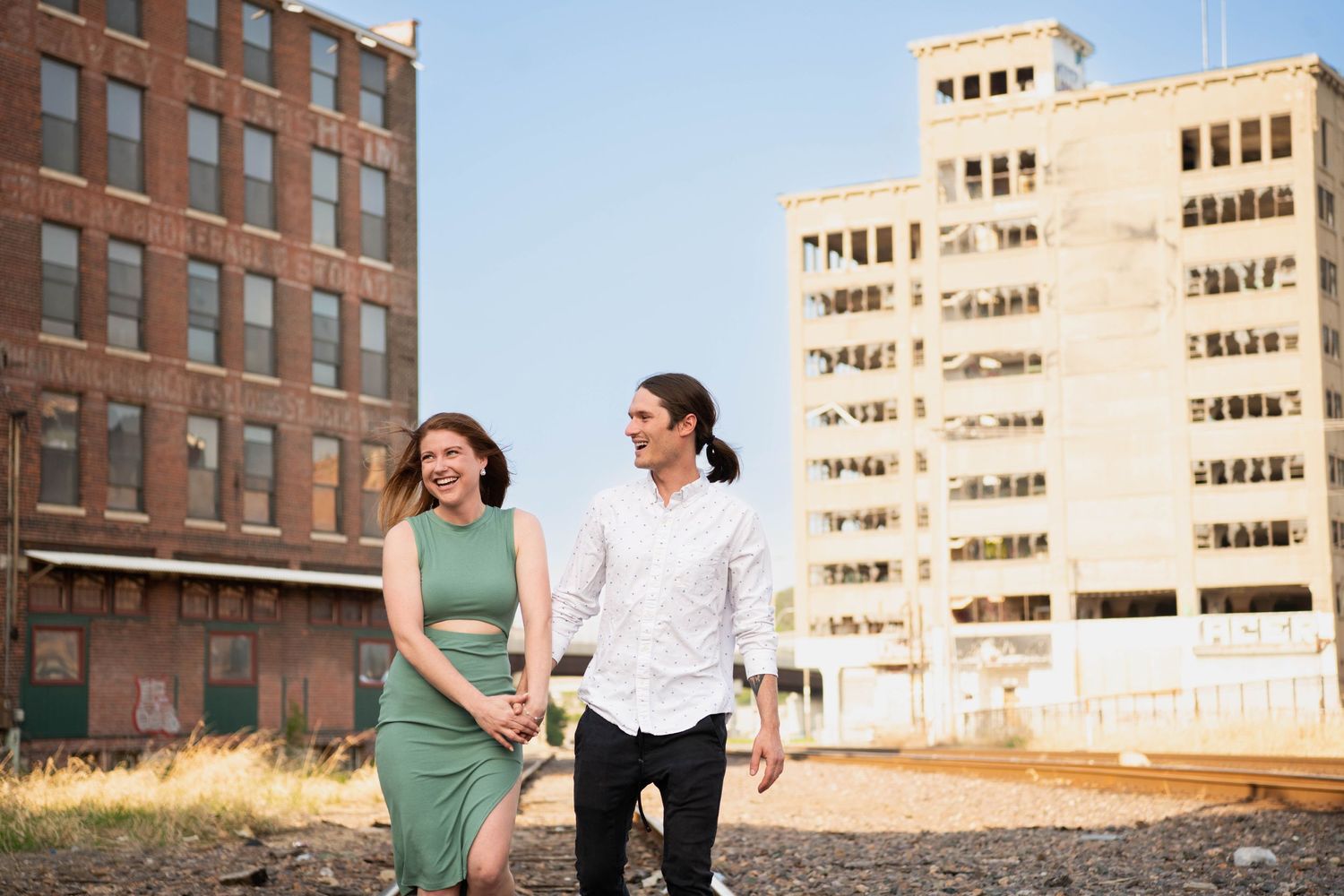 Couple in matching white and green outfits walking together near urban buildings and tall apartment complex.