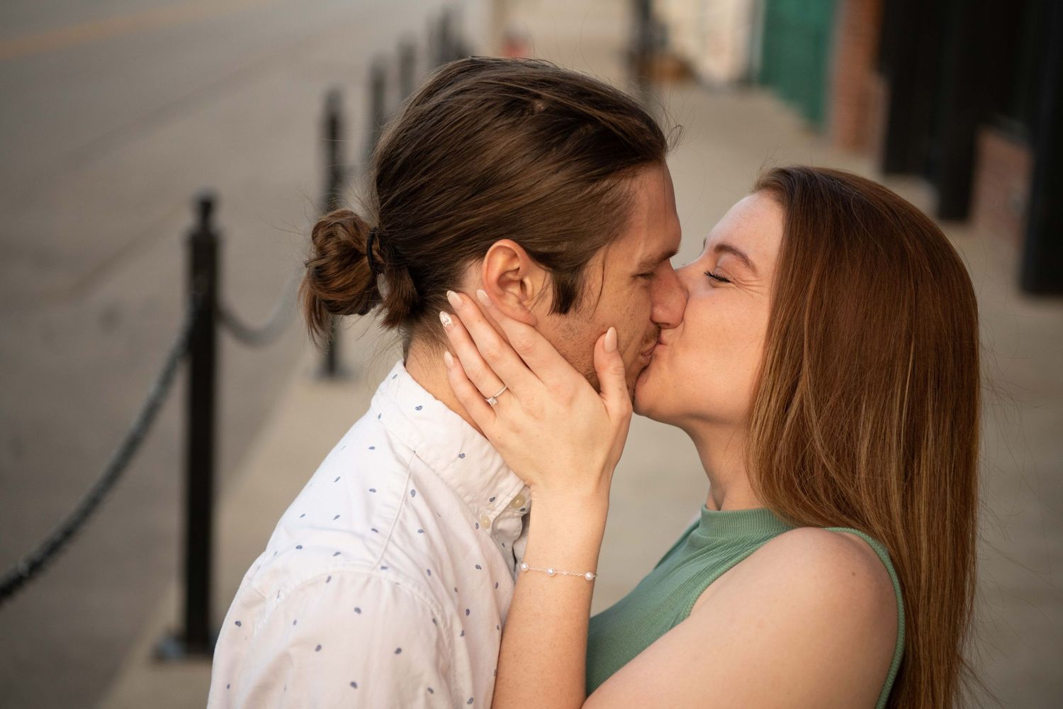 Tender romantic moment shared between couple on city sidewalk.