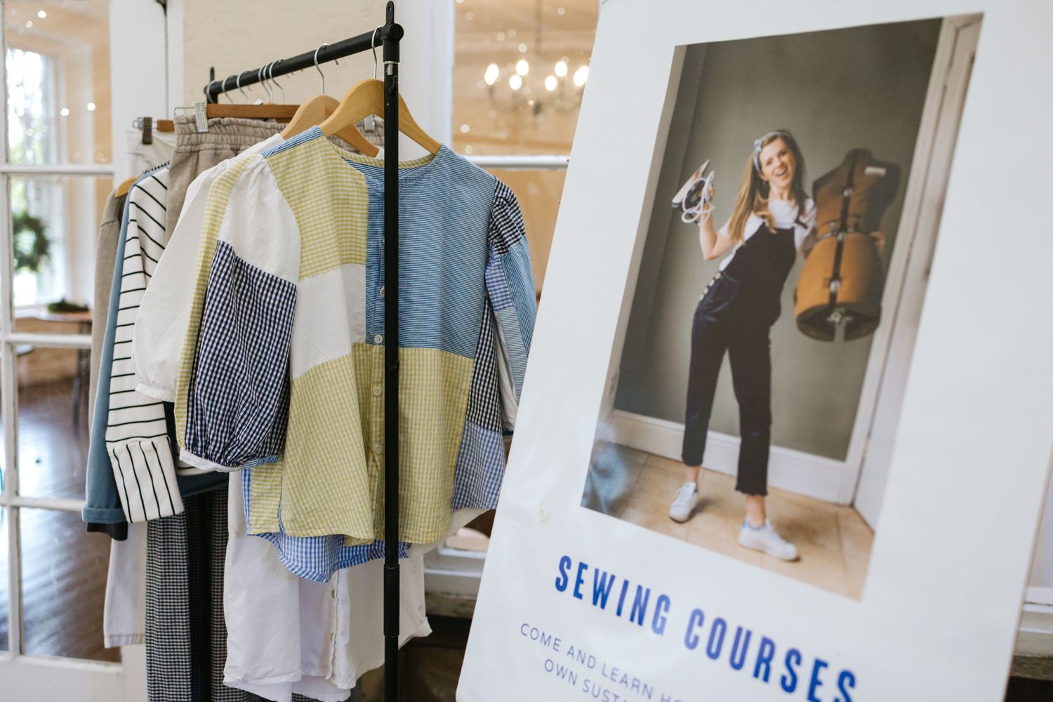 Display of clothing and a sewing course promotional poster in a boutique setting.