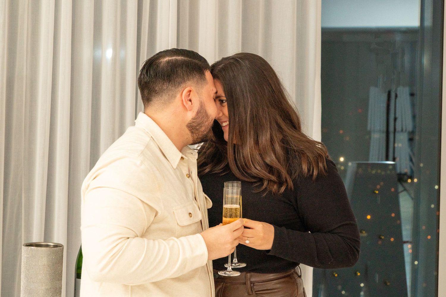 Romantic couple sharing champagne moment in elegant indoor setting.