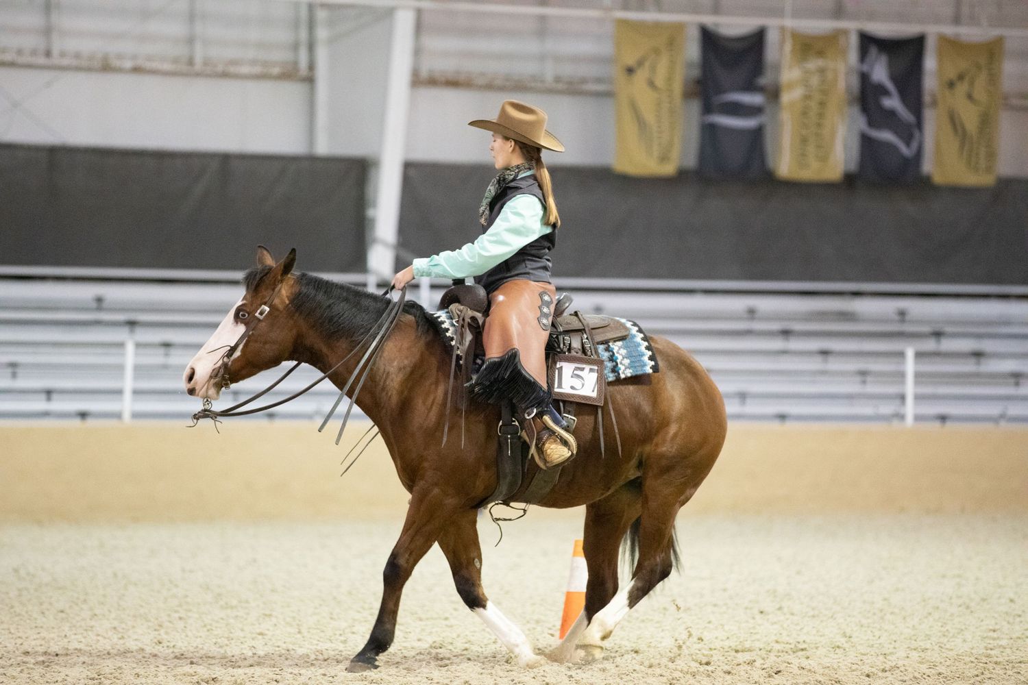 Western rider practicing reining maneuvers in indoor arena.
