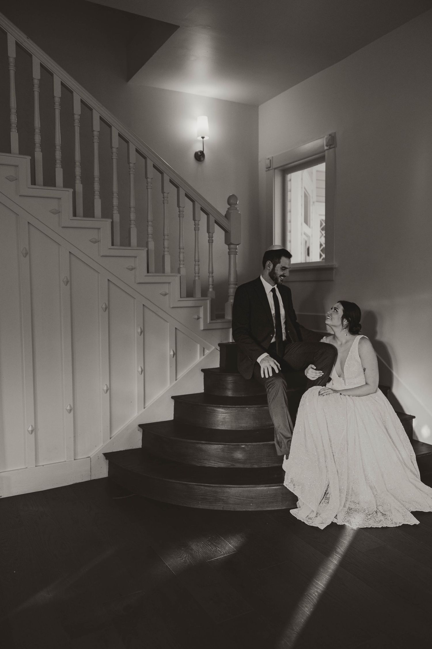 Vintage black and white photo of couple sitting on elegant indoor staircase.
