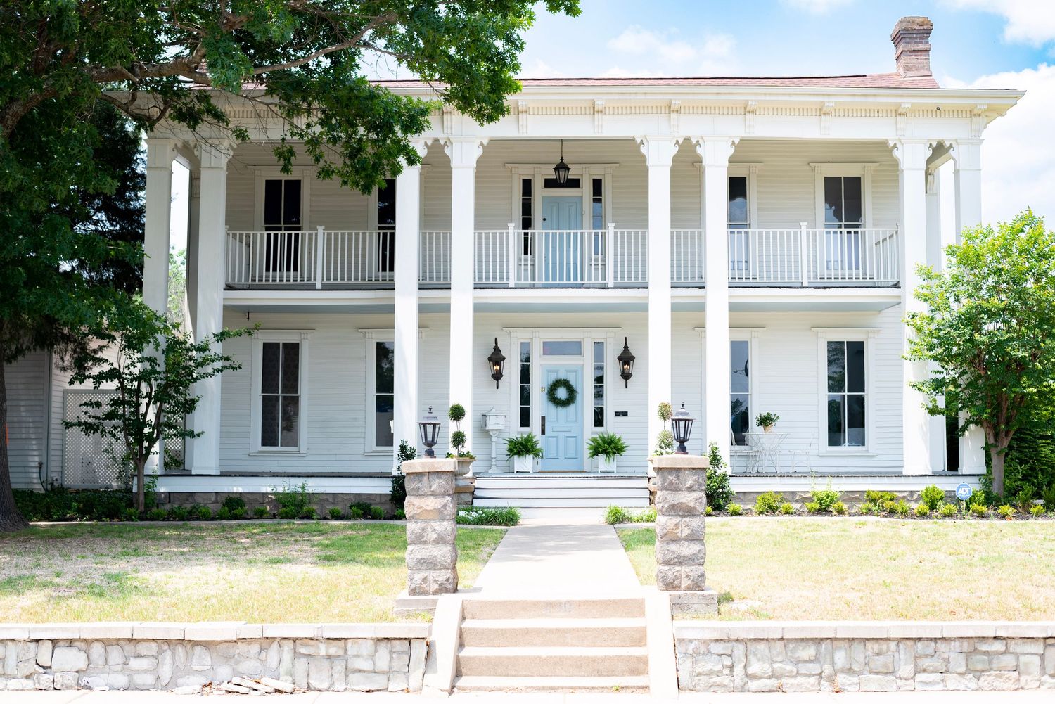Grand white antebellum mansion with two-story columns and wraparound porch in traditional Southern style.