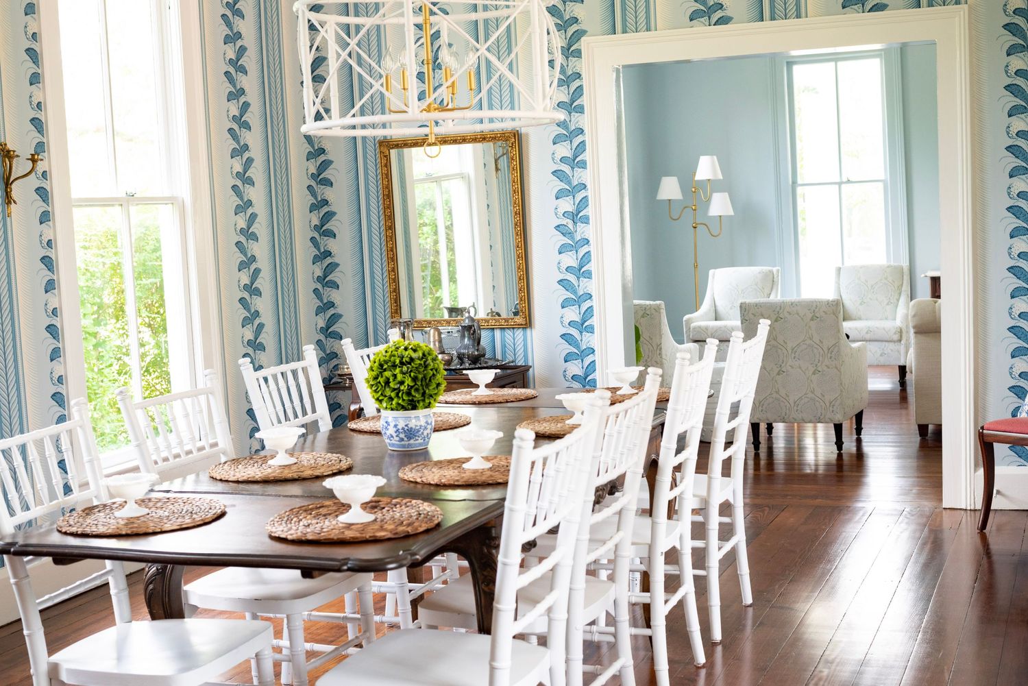 Elegant white dining room with blue and white wallpaper and traditional wooden chairs.