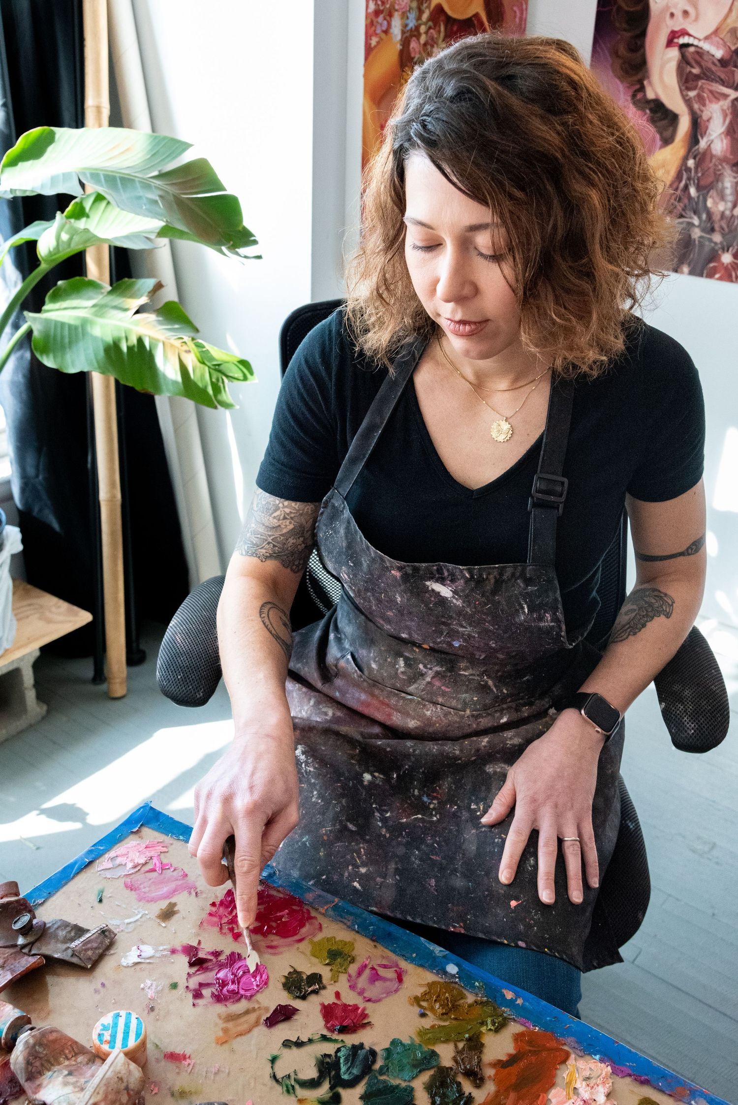 Artist working at a table with paint and art supplies while creating new pieces.