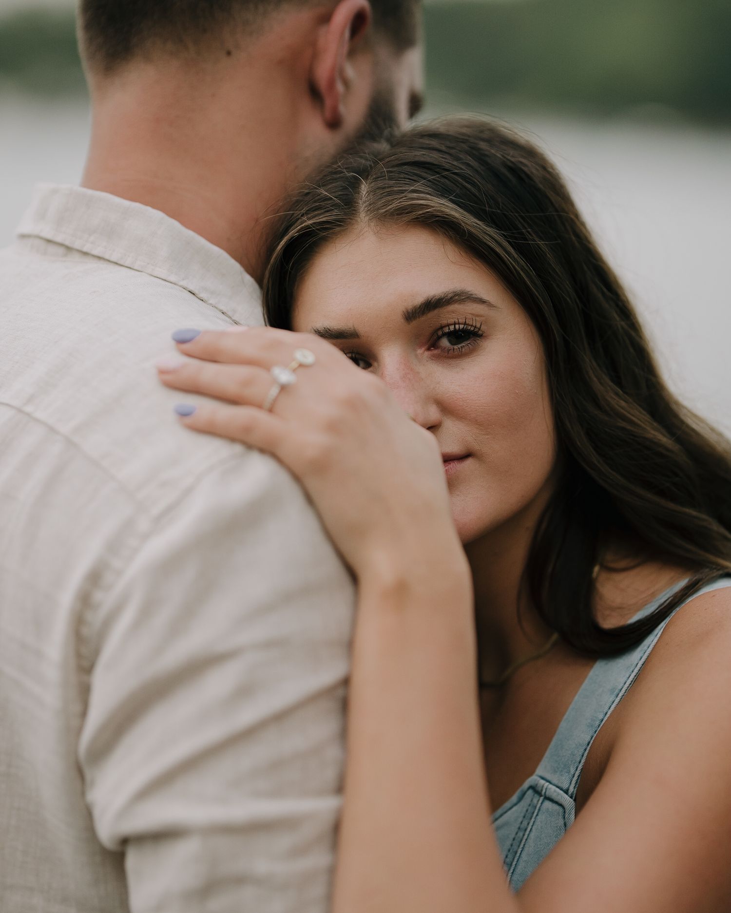 Romantic embrace captured in soft evening light showing an engagement ring.