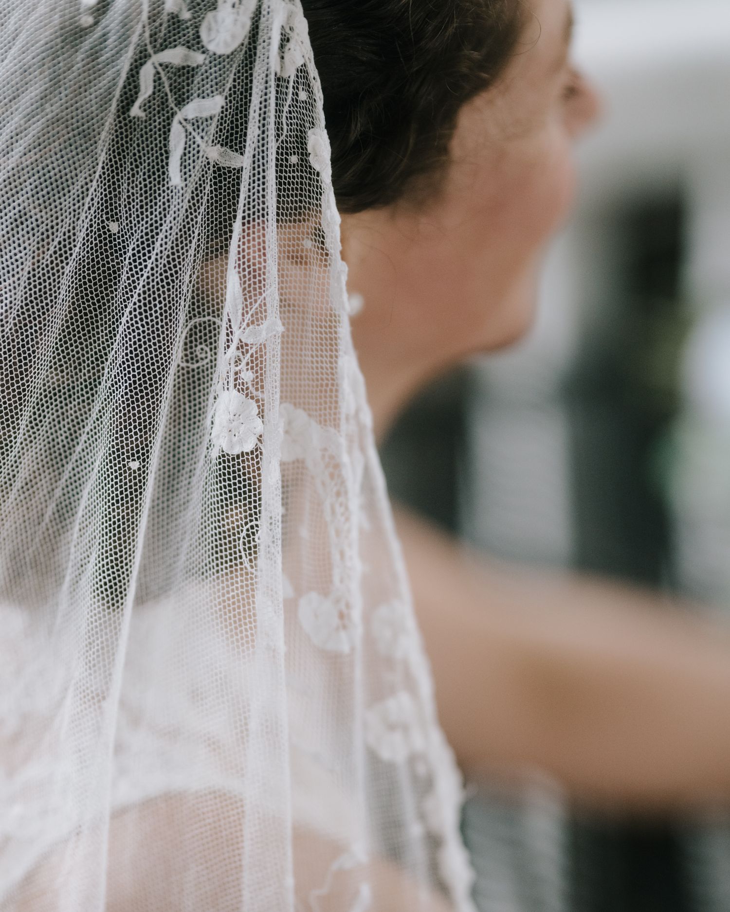 A close-up detail shot of delicate lace wedding veil with floral embroidery.