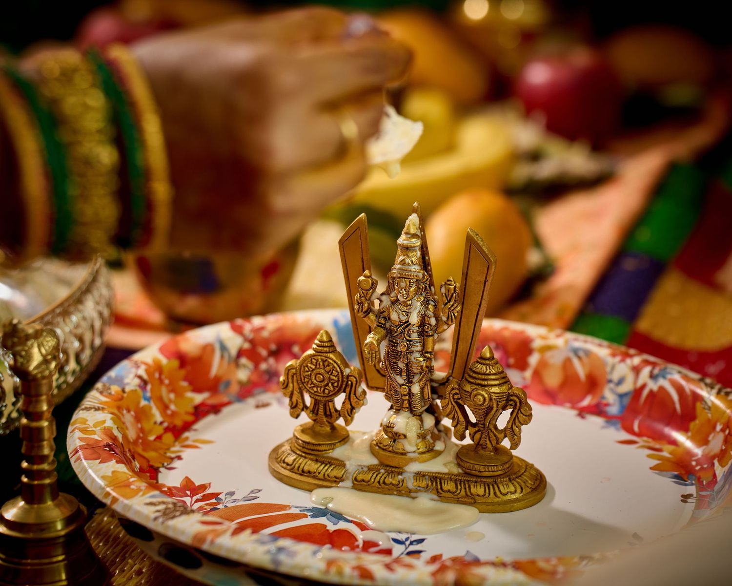 Decorative golden deity figurine displayed on ornate floral plate during Hindu ceremony.