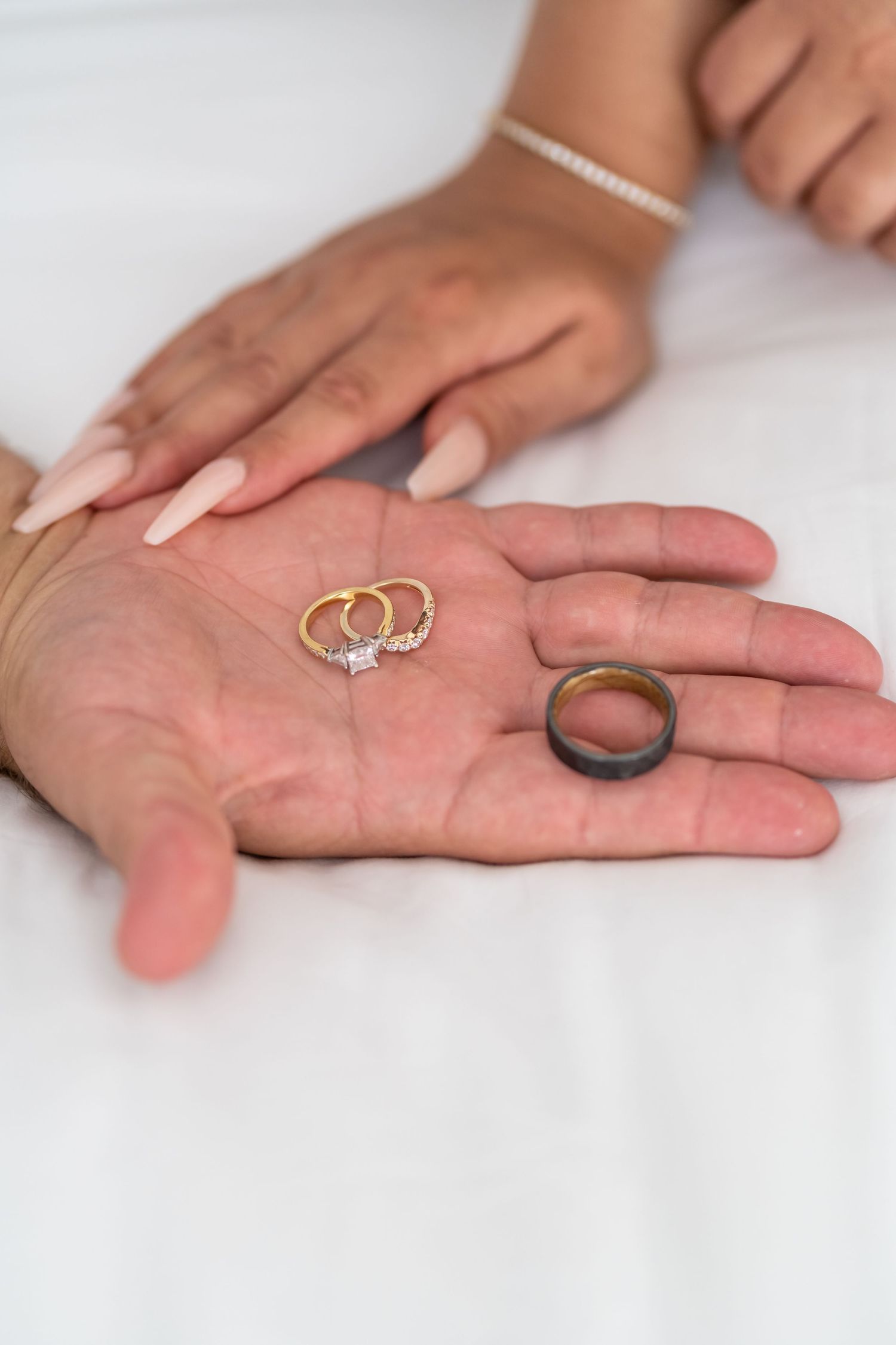 Wedding rings displayed on open palms against white background.