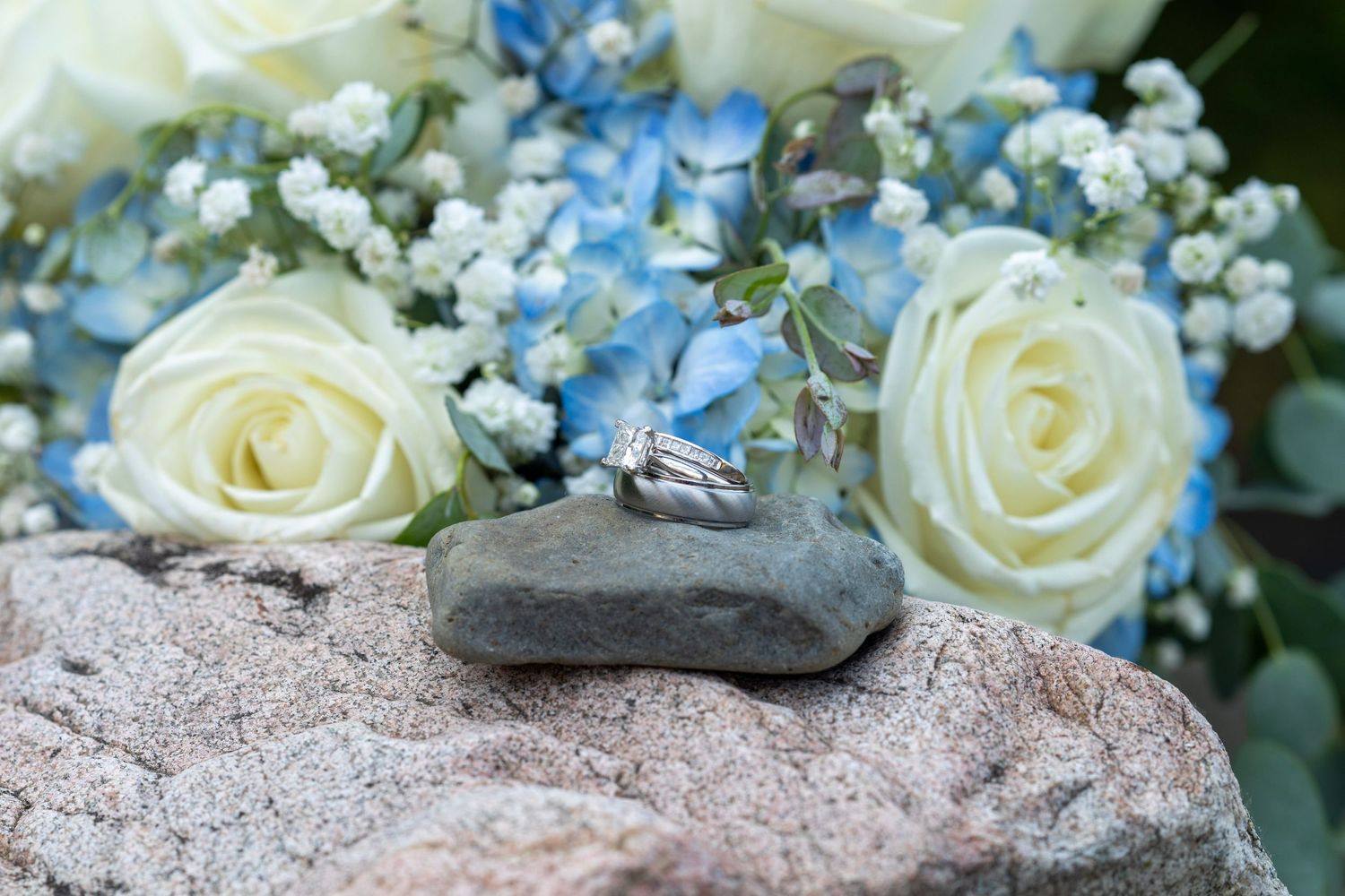 Delicate arrangement of white roses and blue forget-me-nots on stone surface.