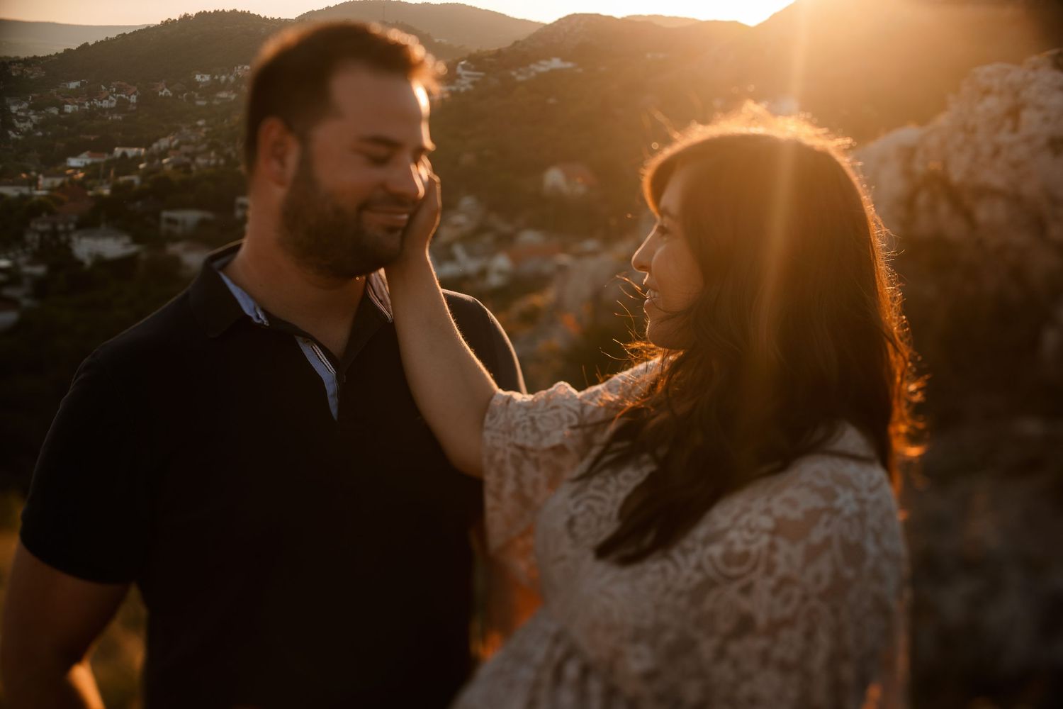 Romantic sunset portrait with couple in golden backlight against mountain backdrop.