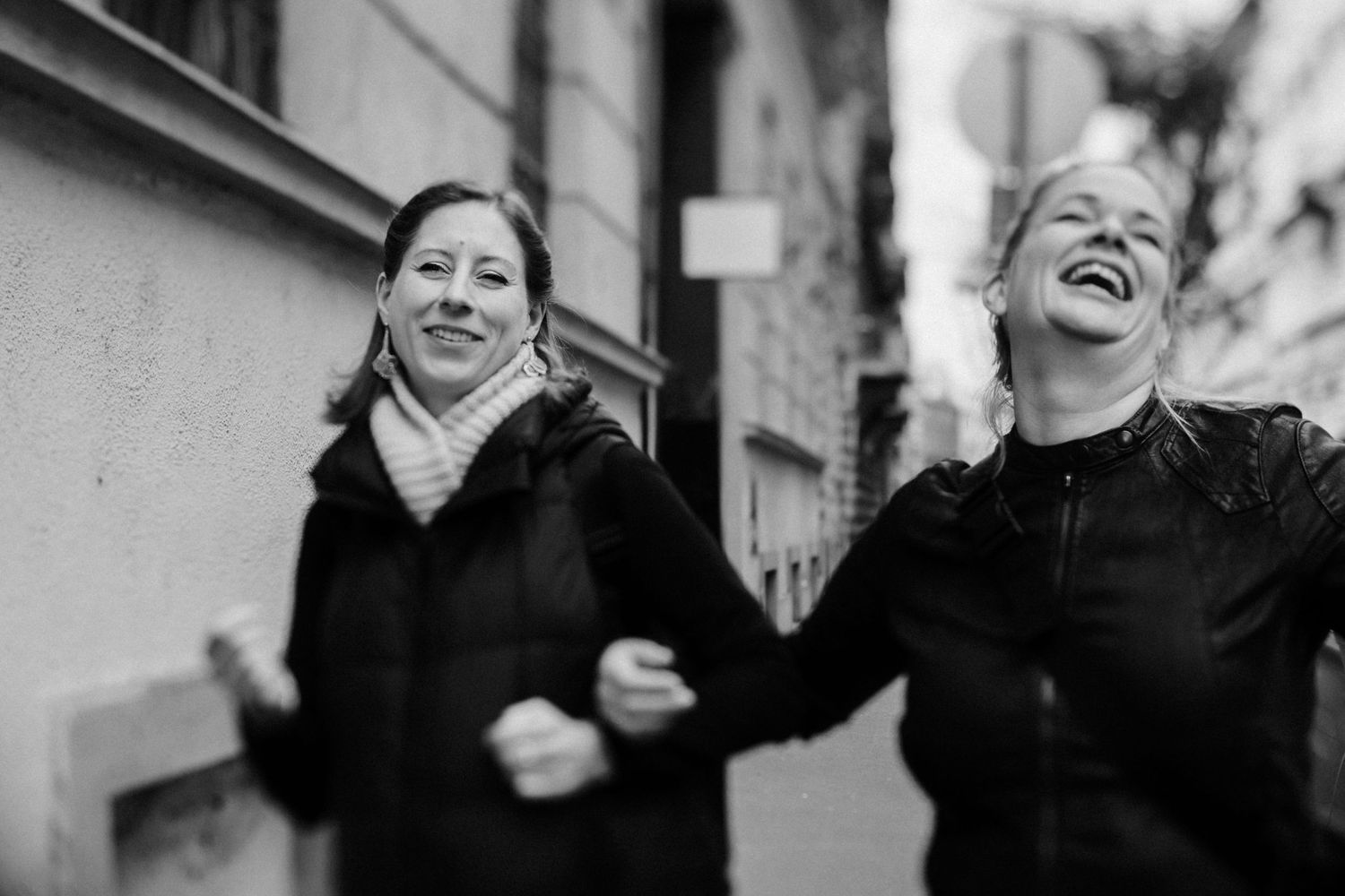 Friends sharing laughter during a casual stroll on an urban street.
