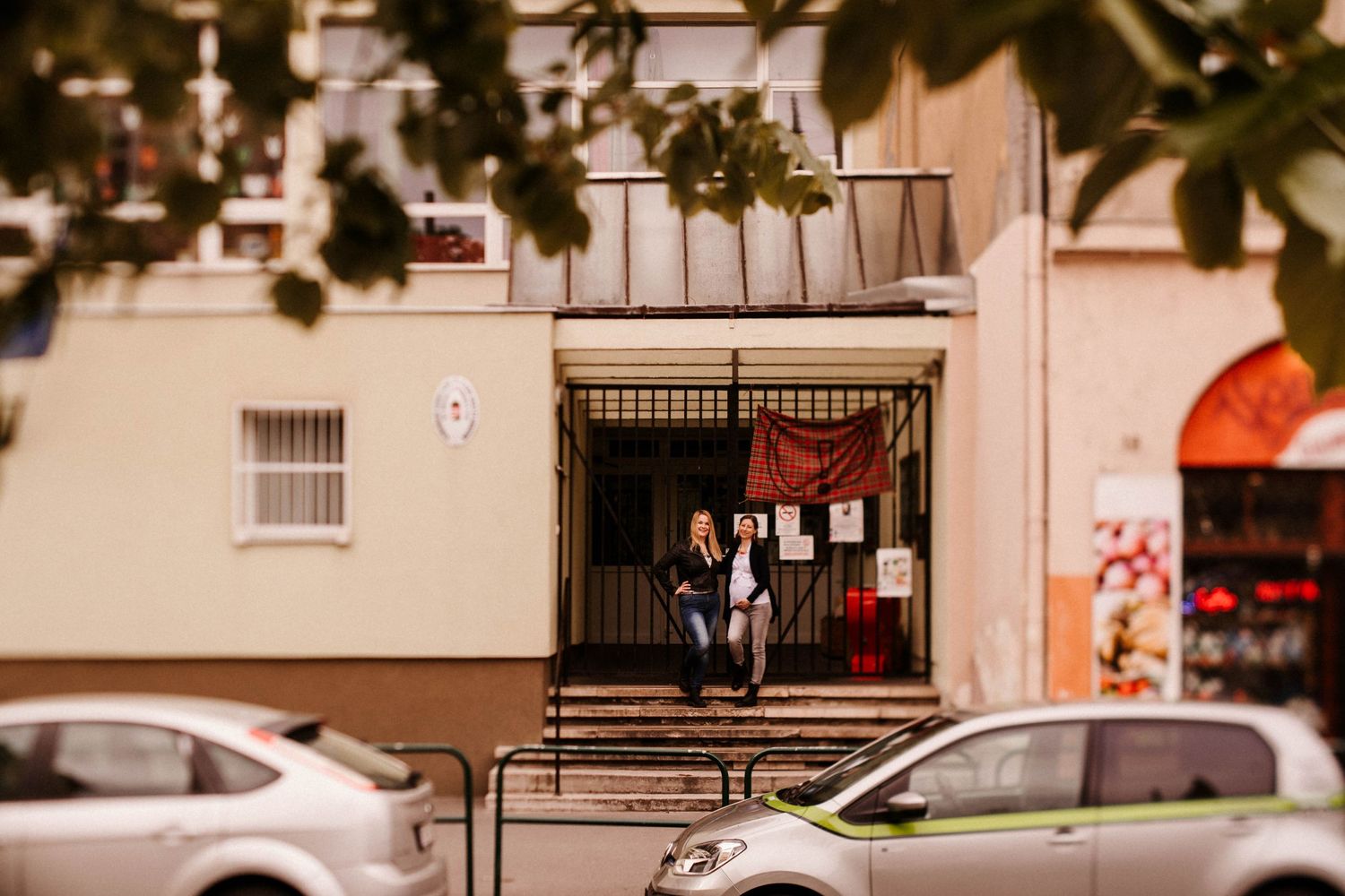 Urban entrance to an apartment building with parked cars on a city street.