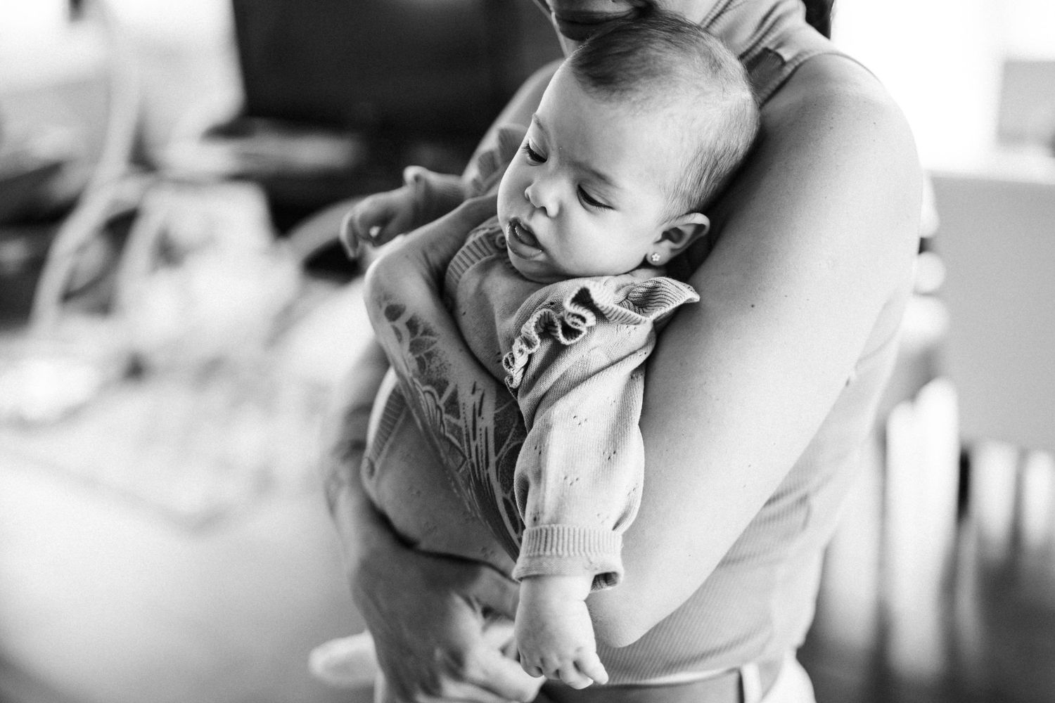 Black and white portrait of baby being held in gentle embrace.