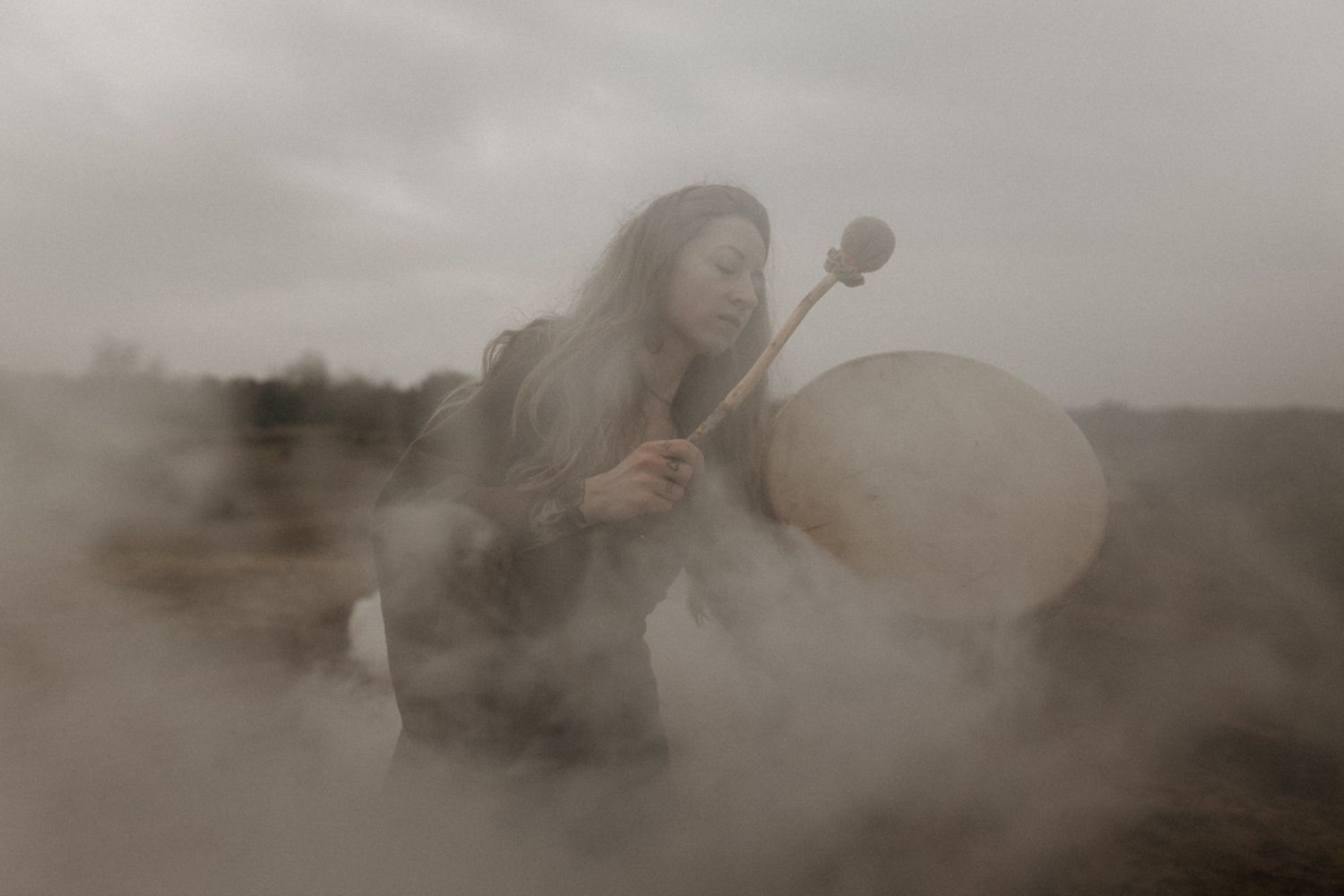 Ethereal photograph of drum ceremony in misty natural setting.