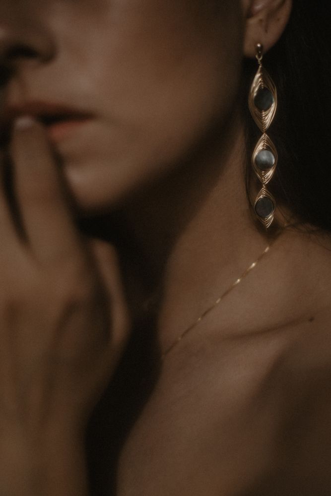 Artistic close-up of vintage-style twisted crystal earring against dark background.