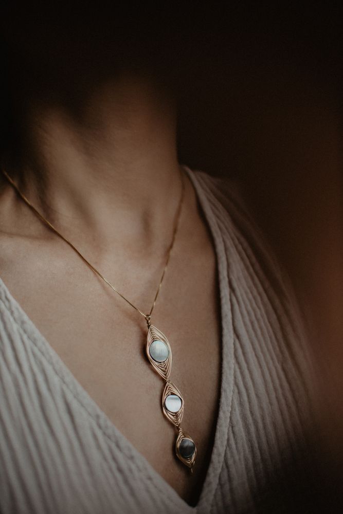 Elegant crystal pendant necklace on cream colored fabric in moody lighting.