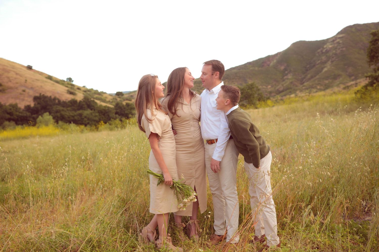 Family gathered together in sun-kissed mountain meadow.